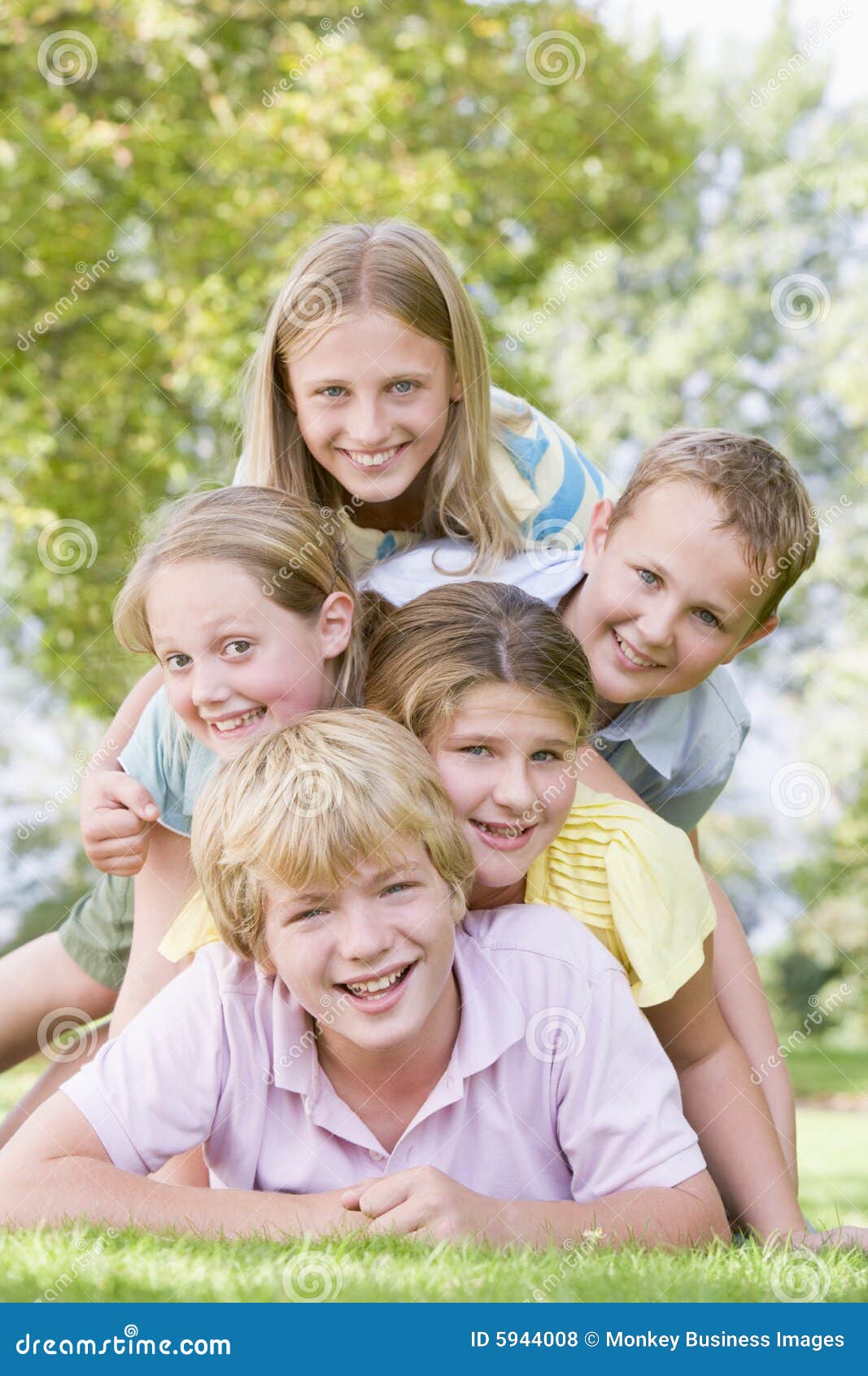 five young friends piled on each other outdoors