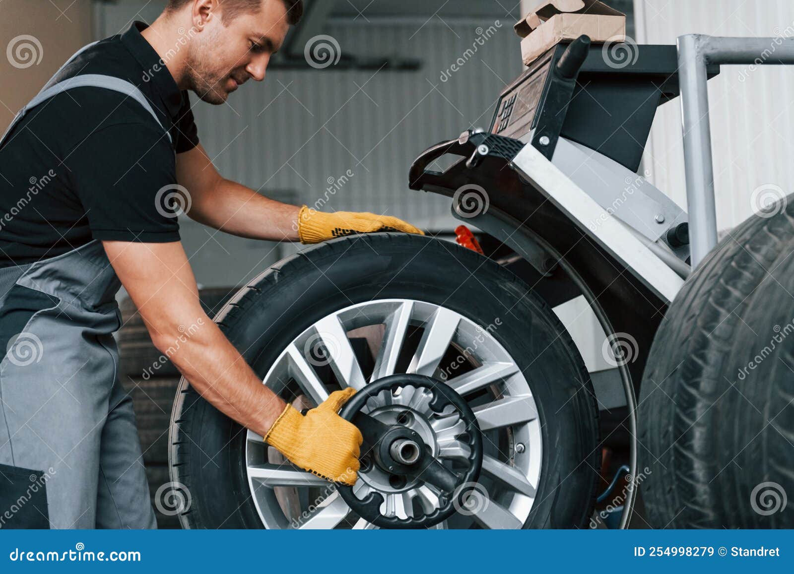 Fixing the Tire. Man in Uniform is Working in the Auto Service Stock