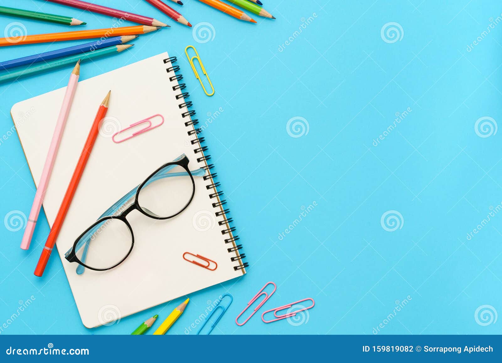 Flachbild-Foto des Büroschreibtisches mit farbenfarbenfroher Bleistift, Büroklammer, Briefheft, Brille, Topansicht des Kopierraums