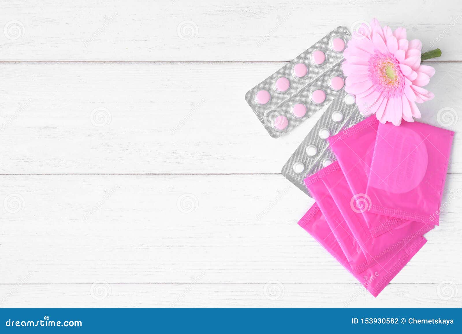 flat lay composition with menstrual pads, pills and flower on white wooden table. gynecology concept