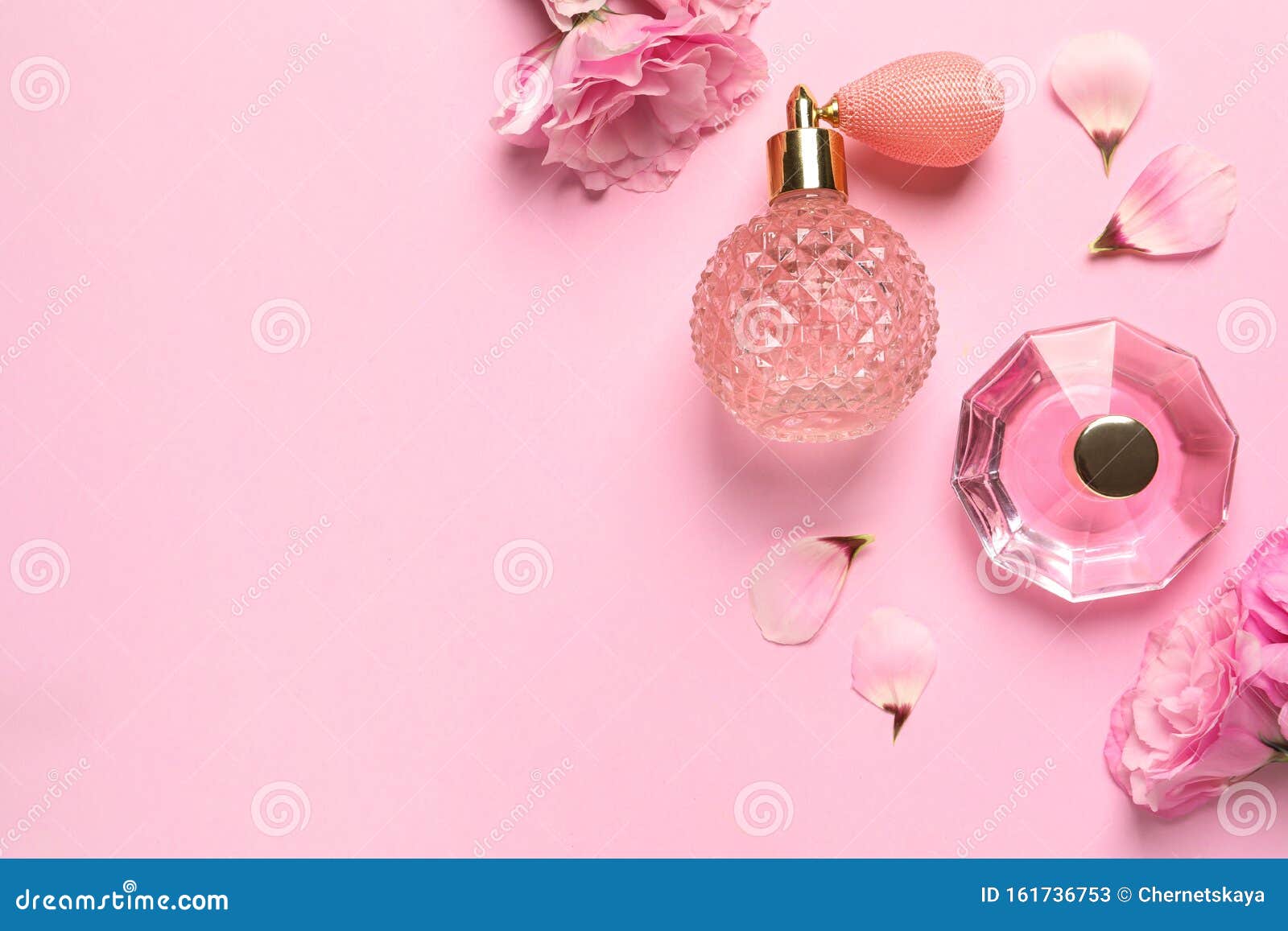 flat lay composition with perfume bottles and flowers on pink background, space for text