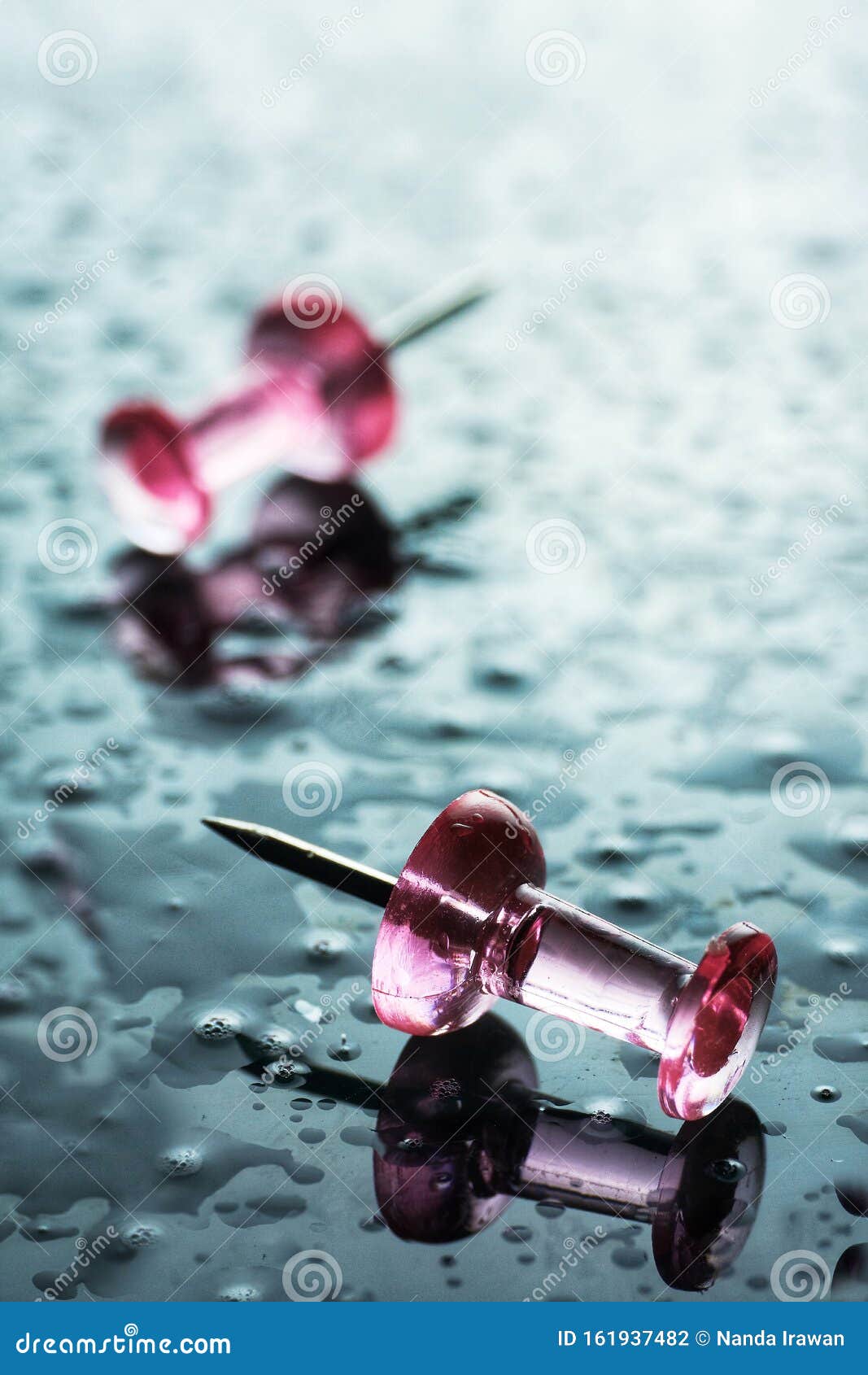 flat lay still life photography of push pin on blue wet background. close-up photo of two push pin pink