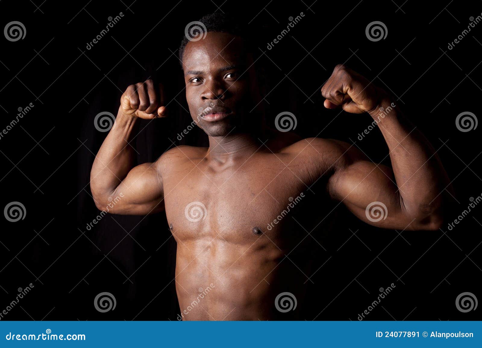 Flex muscles on black. A man flexing his muscles on a black background.