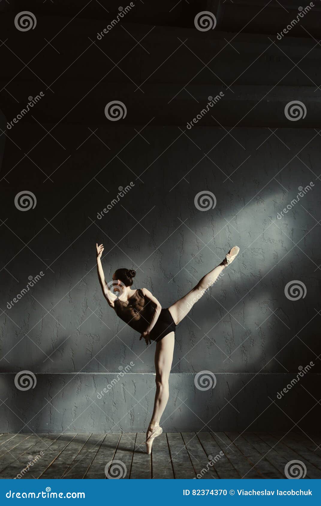 Flexible Ballet Dancer Stretching in the Dark Lighted Studio Stock