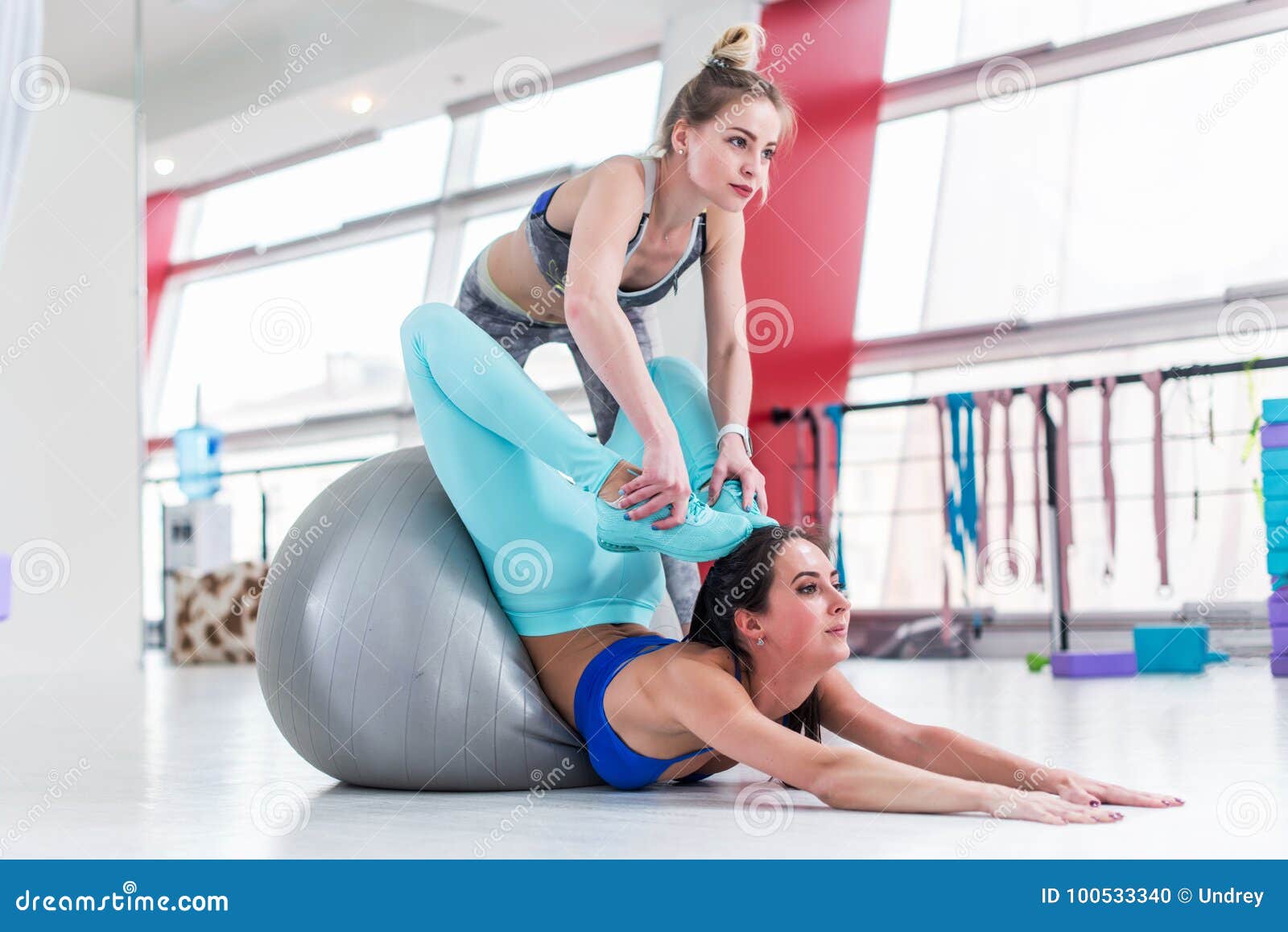 Flexible Woman Doing Advanced Stretching Exercise. Pretty Female Instructor  Helping Slim Brunette Girl Do Yoga Locust Stock Photo - Image of flexible,  assistant: 100533340