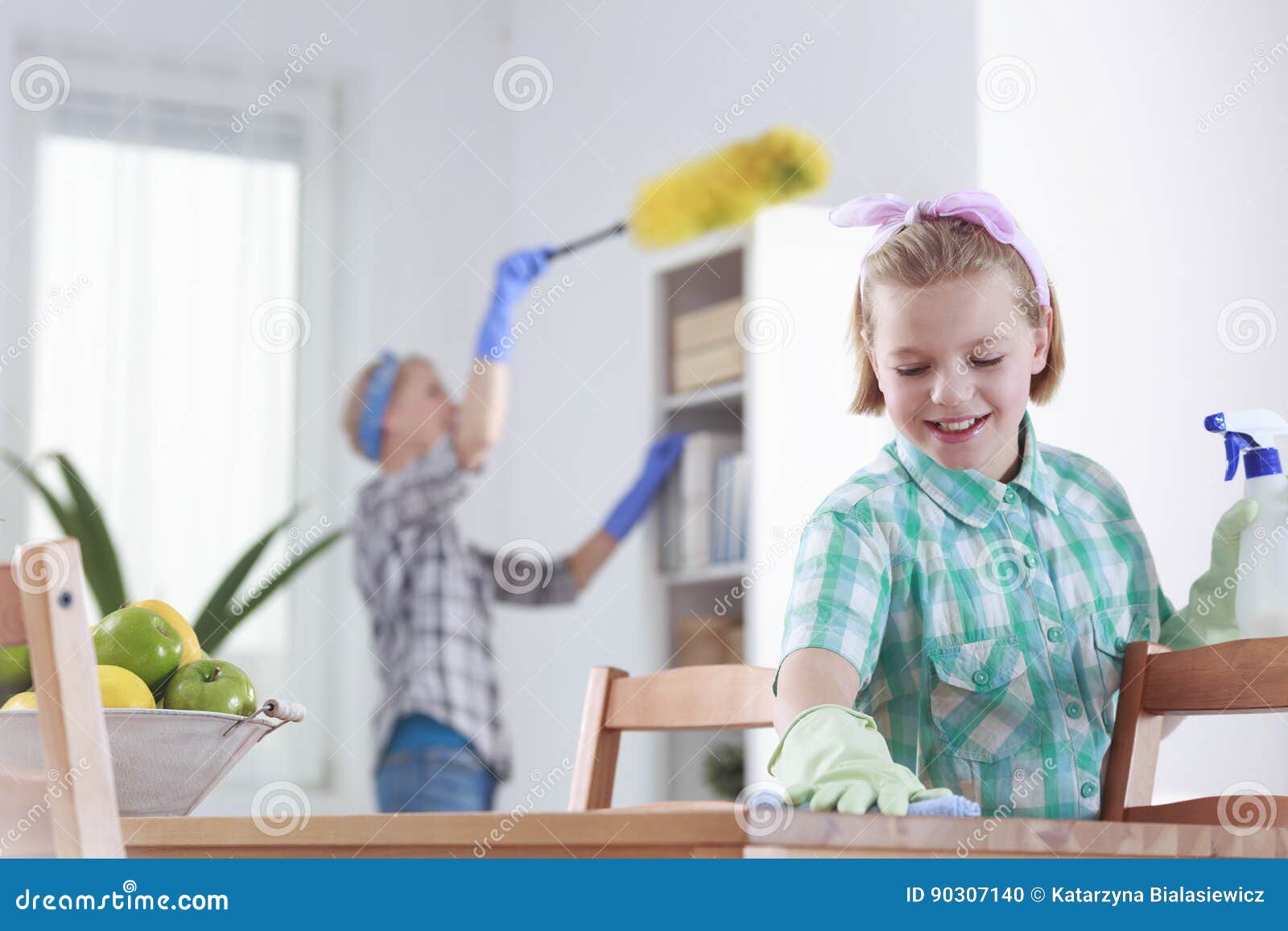 Flicka som hemma gör ren. Le flickan och hennes moder som hemma gör ren