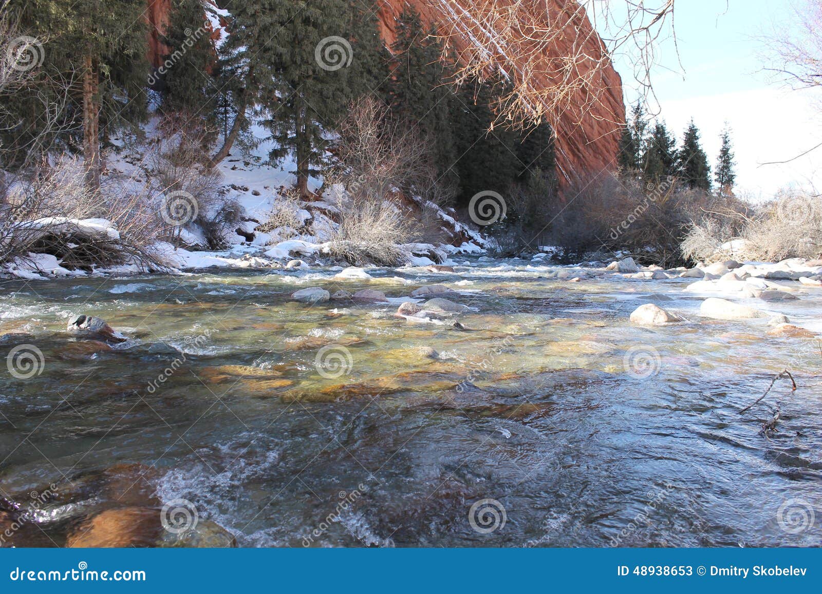 Flod på foten av klippan. Floden på foten av klippan, samlar några små bergfloder, och gå på foten av det enorma rött vagga