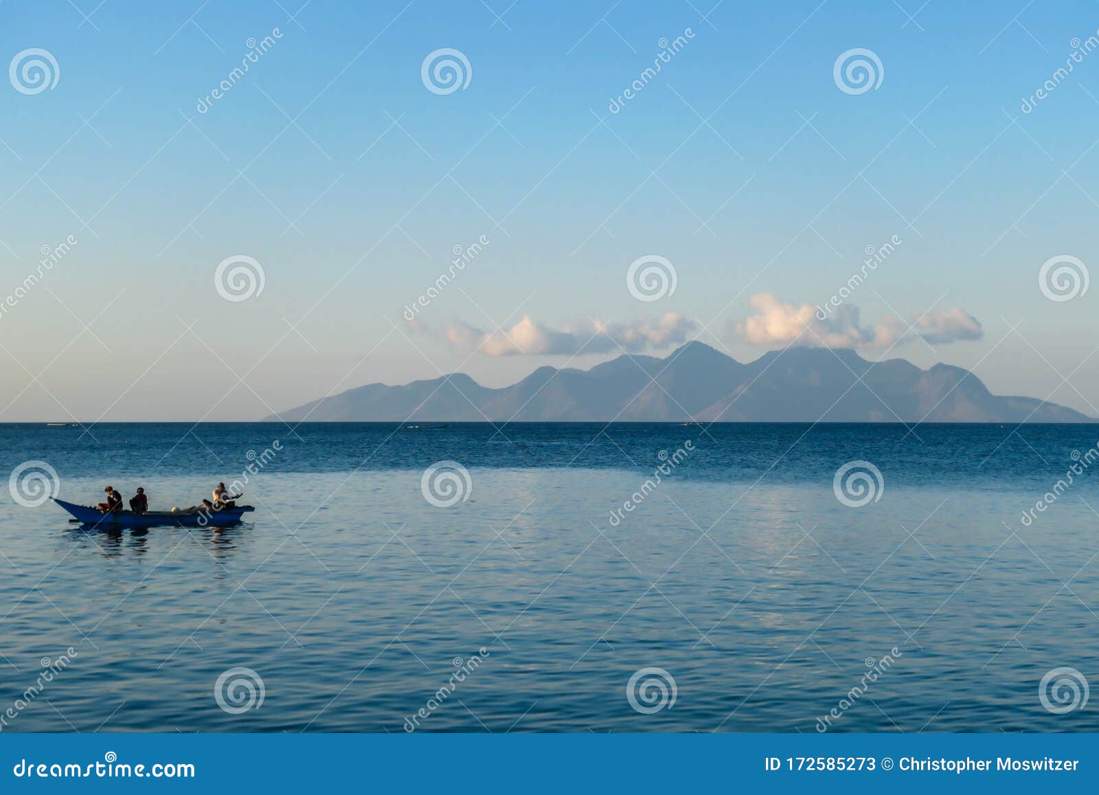 flores/indonesia 20290808: a fishermen`s boat crossing a calm sea near maumere, indonesia there are three men in one small, blue