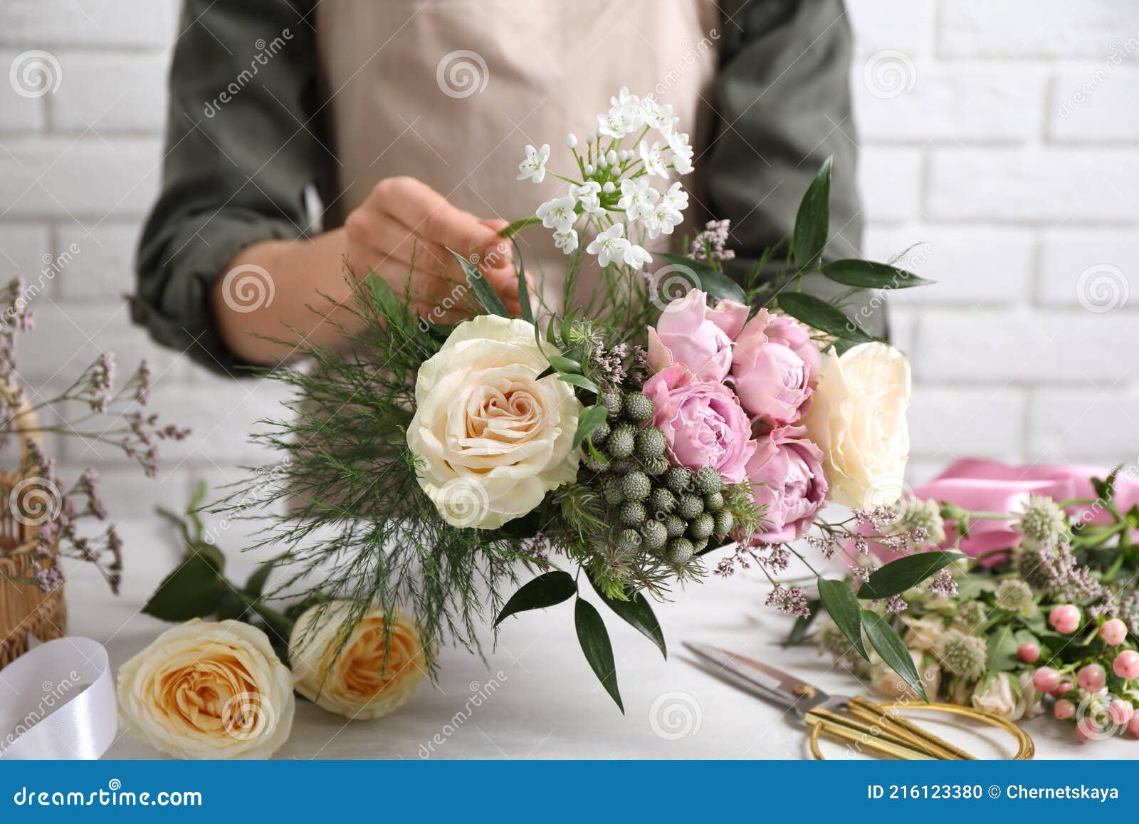 florist making beautiful bouquet at white table, closeup