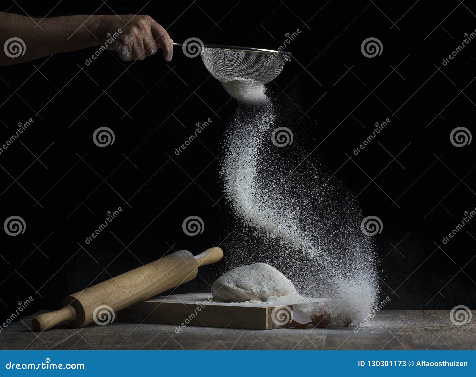 flour is sprinkled over a ball of dough on a wooden board with r