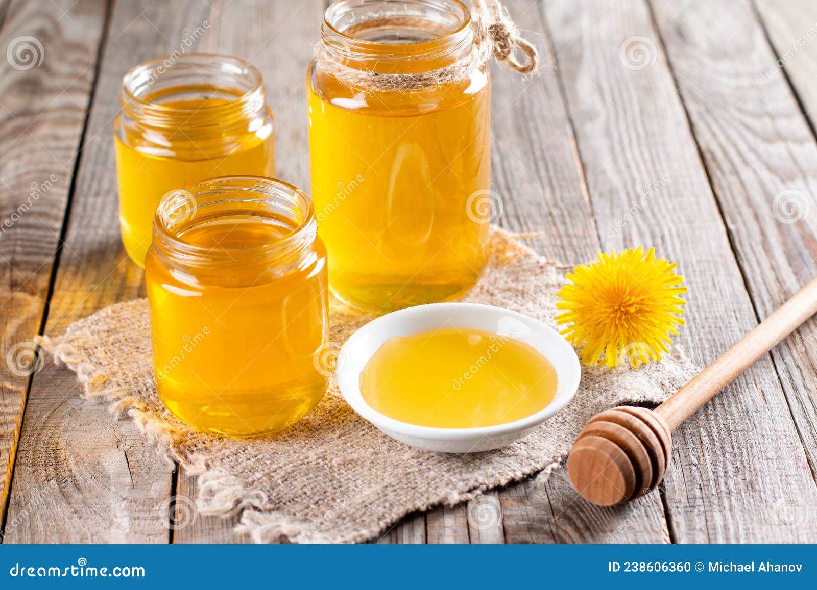 flower honey in a glass jar and dandelions on a table