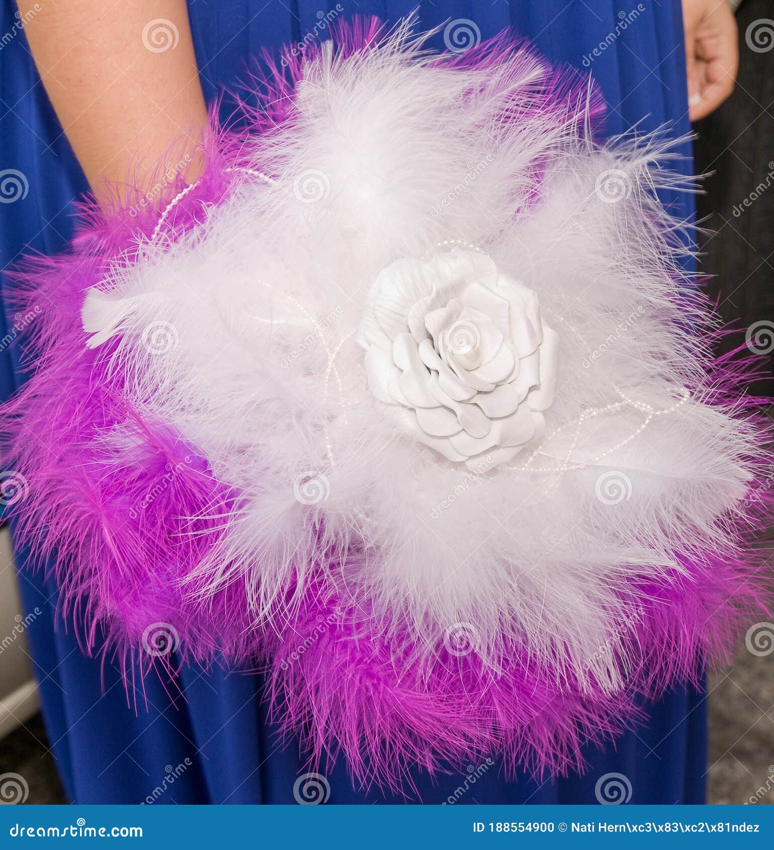 soft bouquet in the hand of a bride made with white and purple feathers with a fabric flower in the center