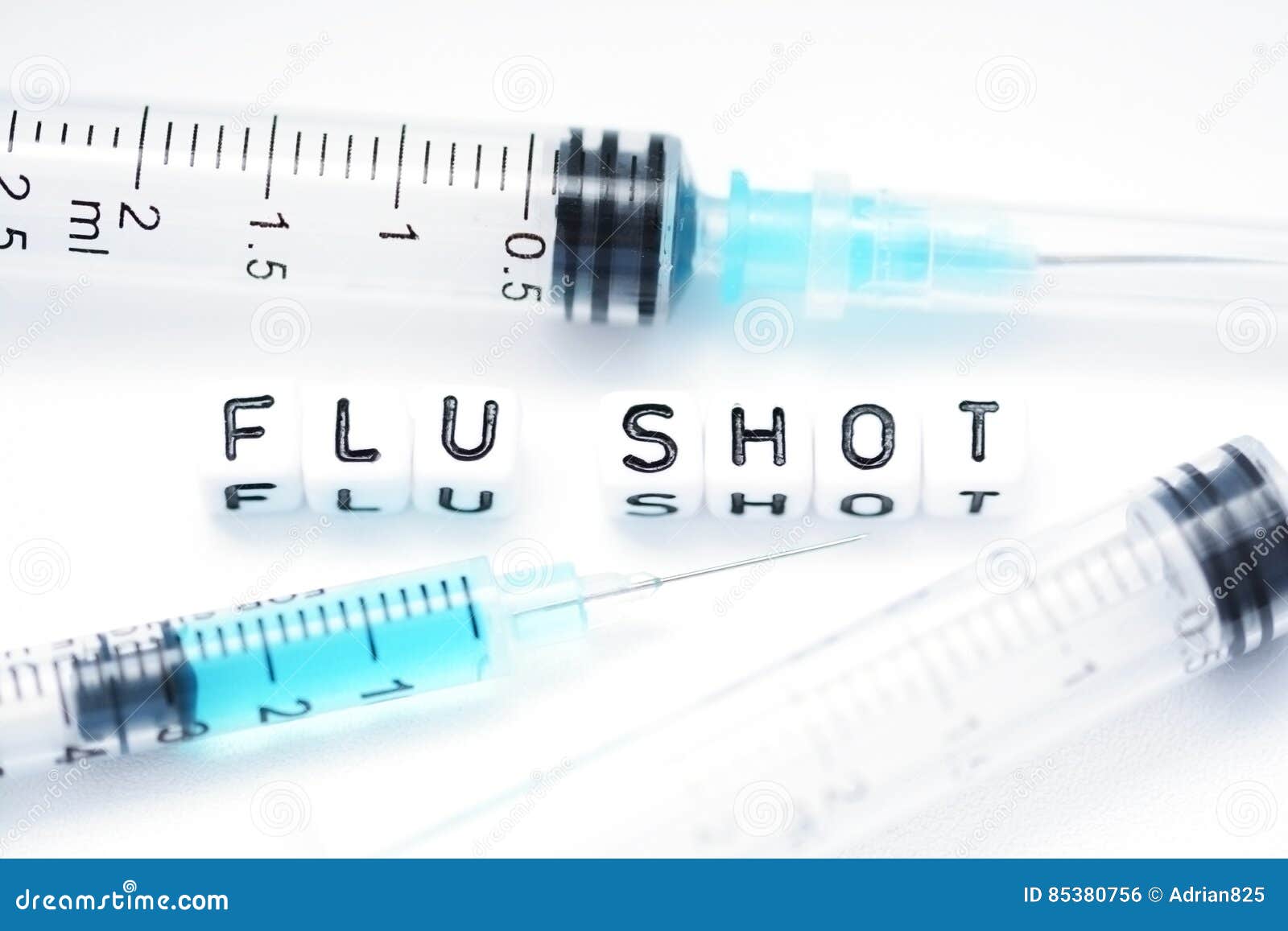 flu shot text spelled with tiled letters standing next to a syringe