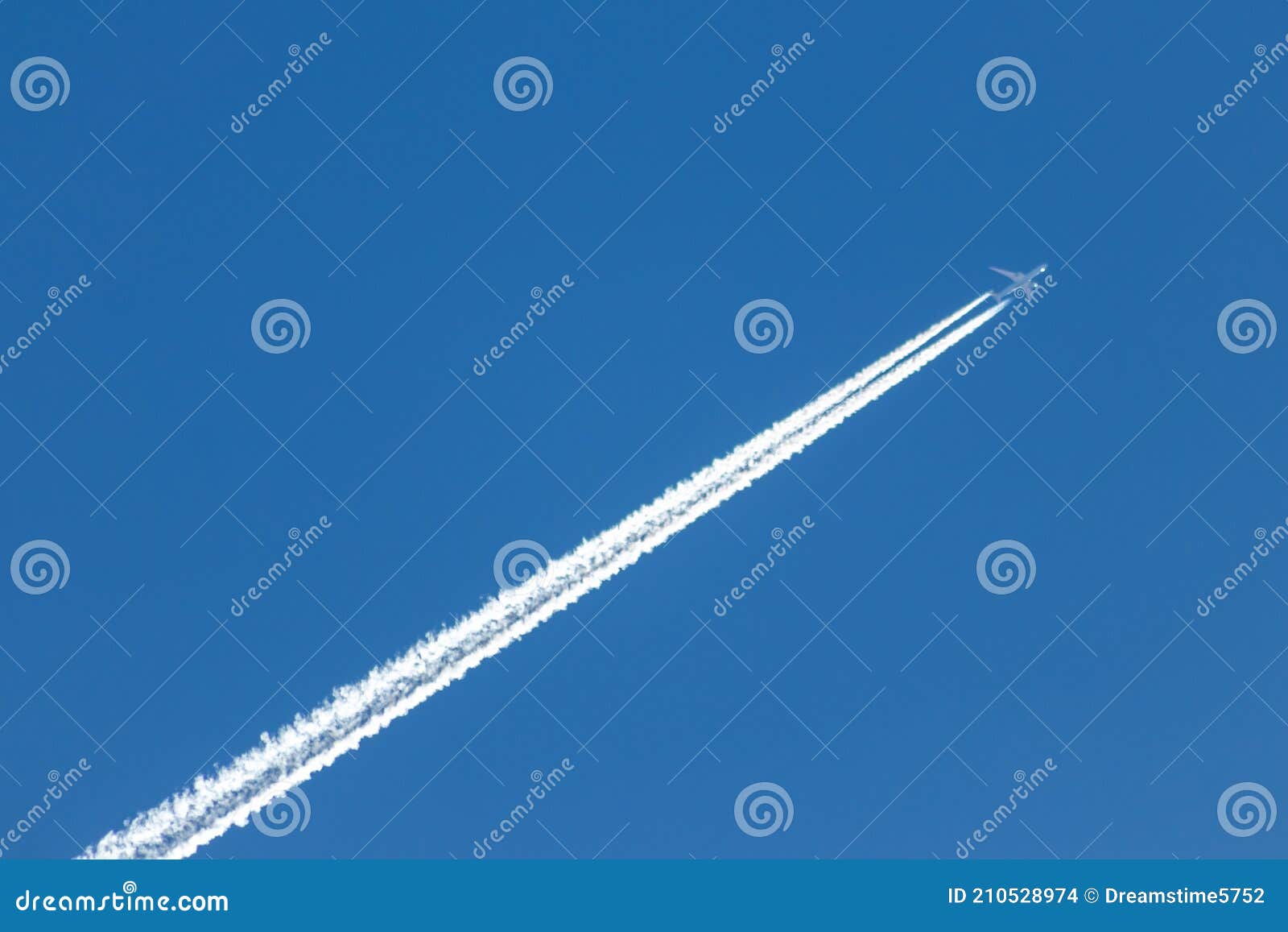 flying airplane on a journey through the blue sky with a long white smoking exhaust plume and jetwash show international transport