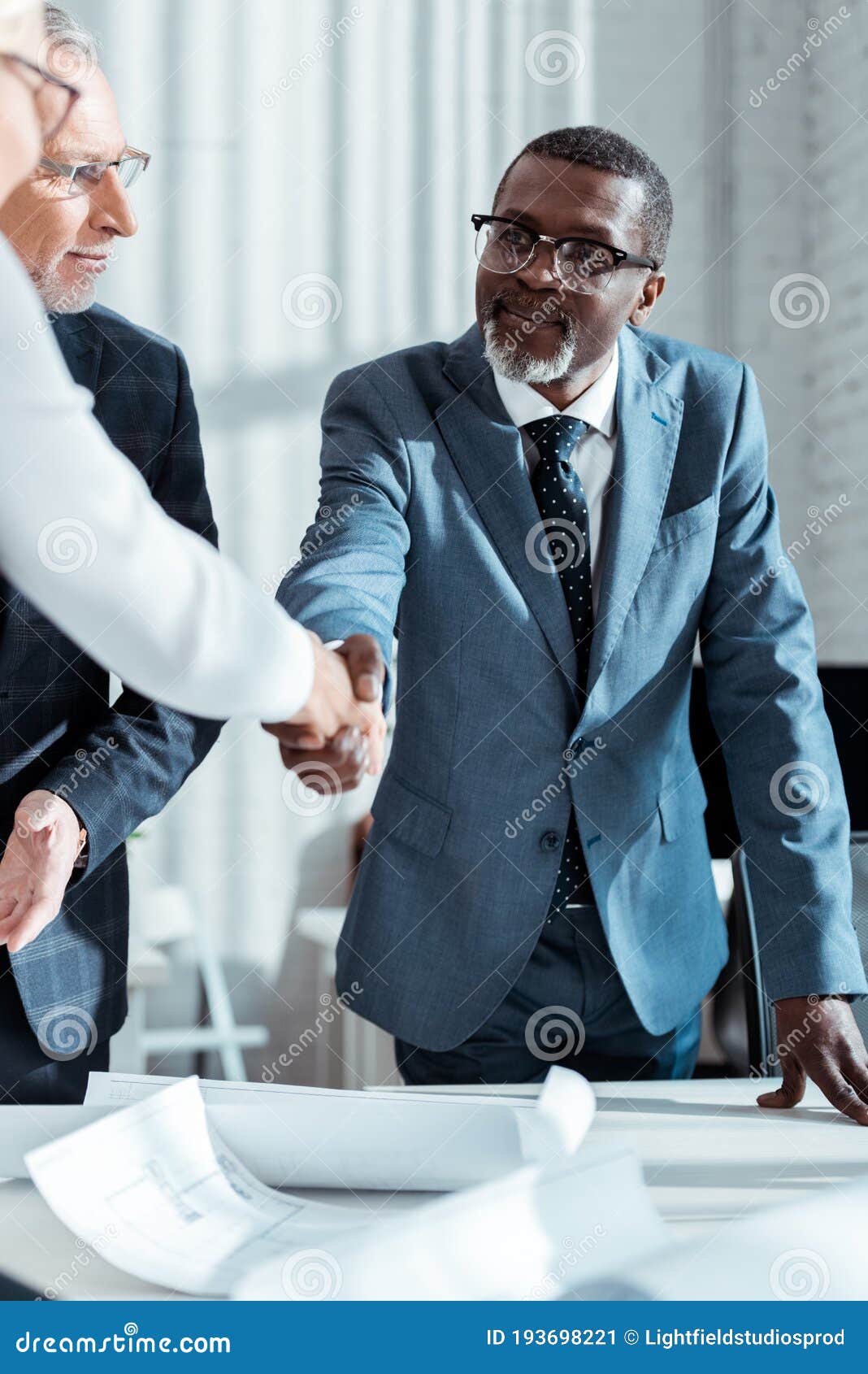 Focus Of Businessman In Glasses Looking At African American Man Shaking Hands With Woman In