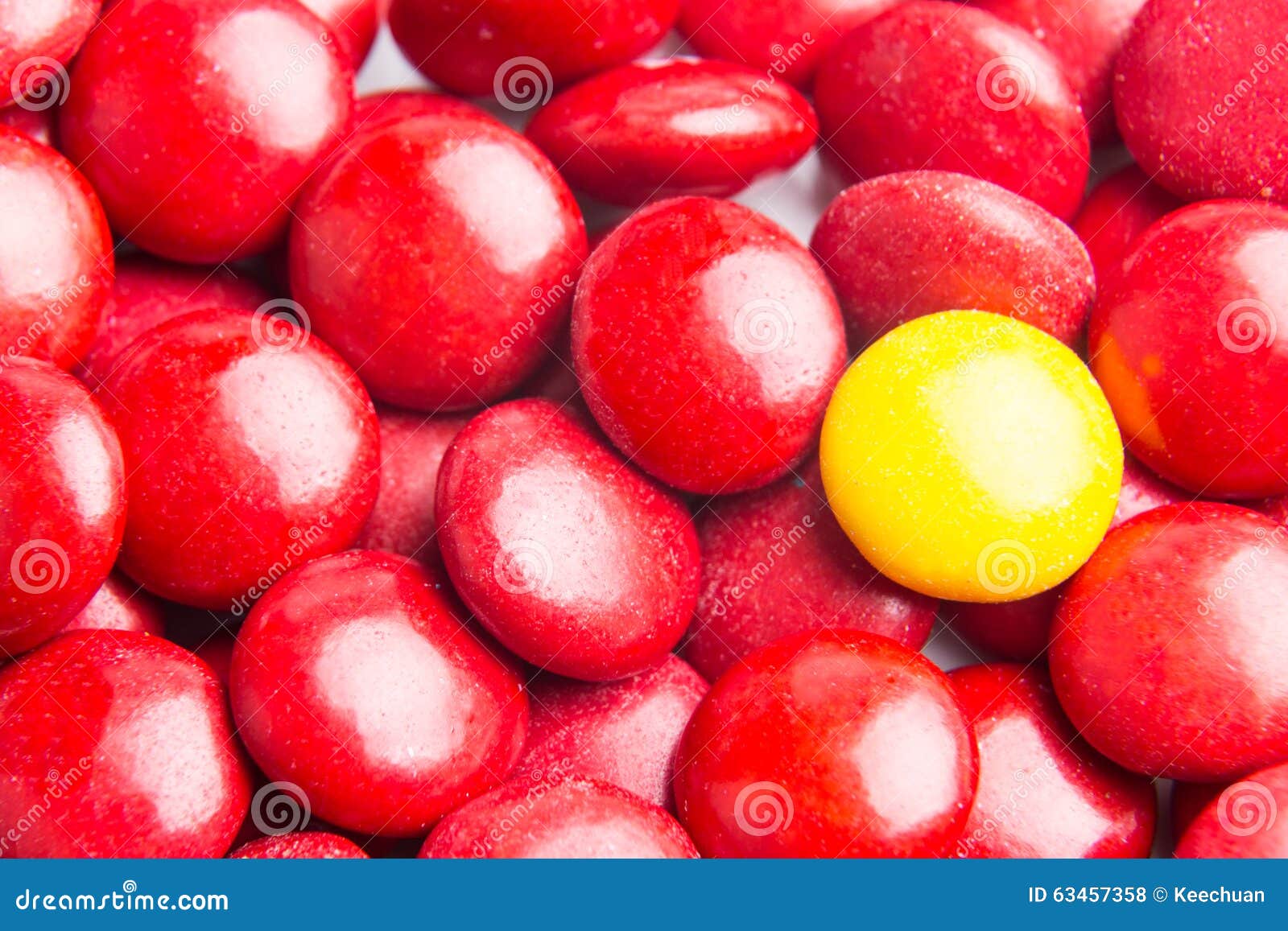 Focus on Yellow Chocolate Candy Against Heaps of Red Candies Stock