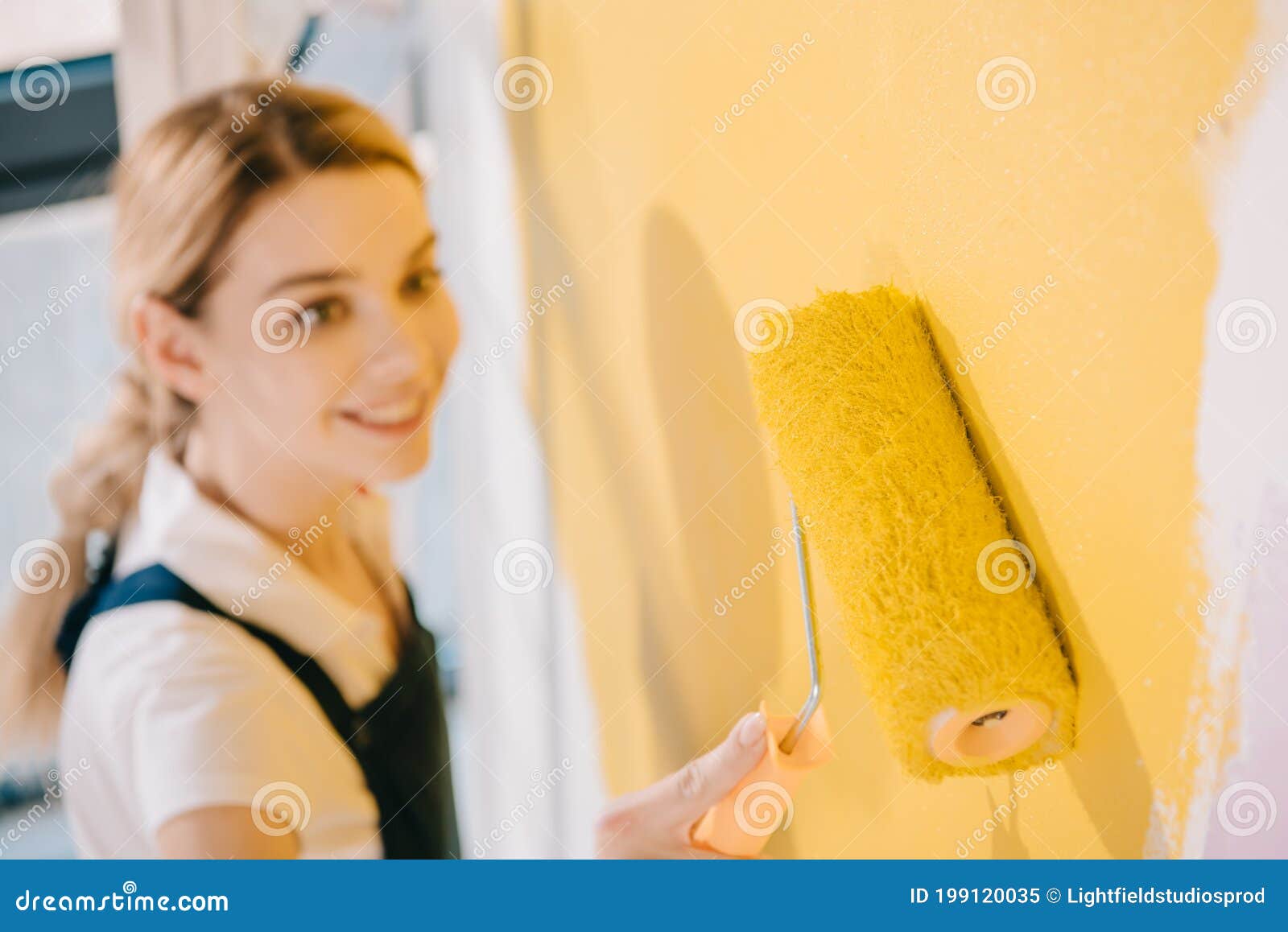 Focus of Young Painter Painting Wall in Yellow with Paint Roller Stock