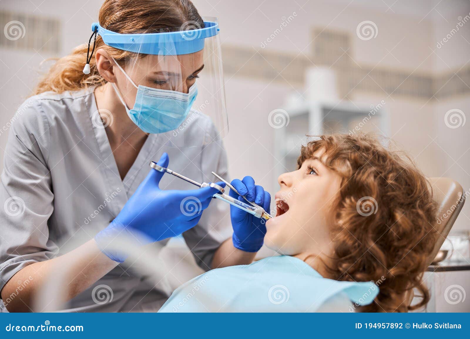 professional dentist is giving anesthesia to a child