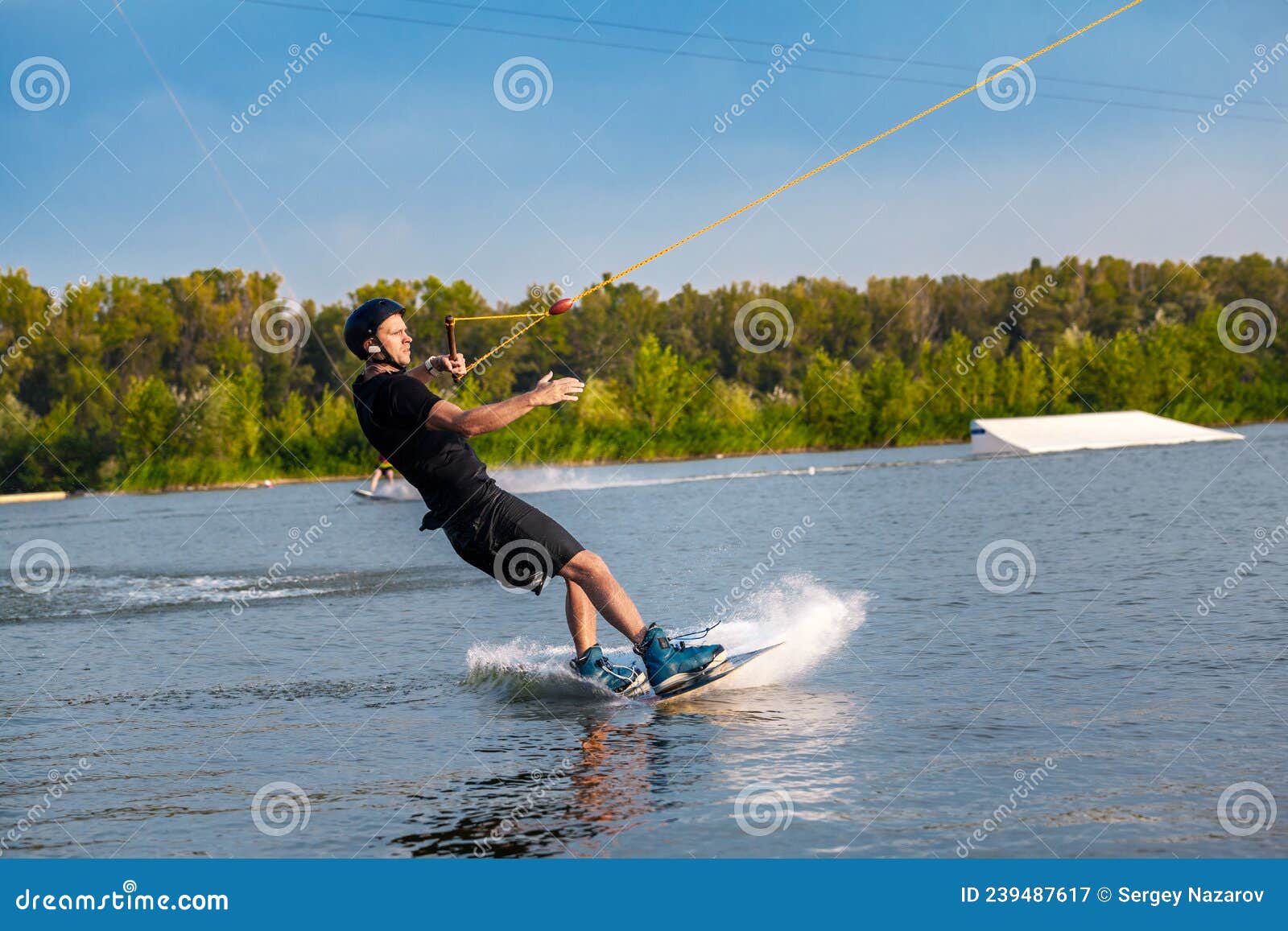 Focused Man Sliding on Wakeboard on Water Surface Holding Tow Rope with