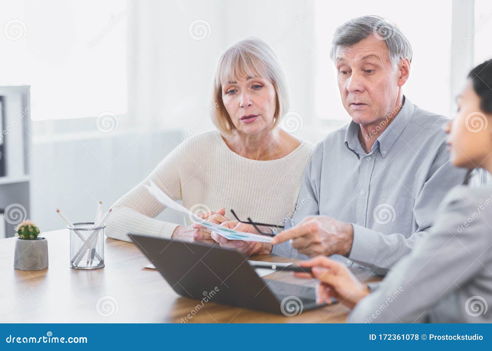 focused mature couple talking to financial advisor at home