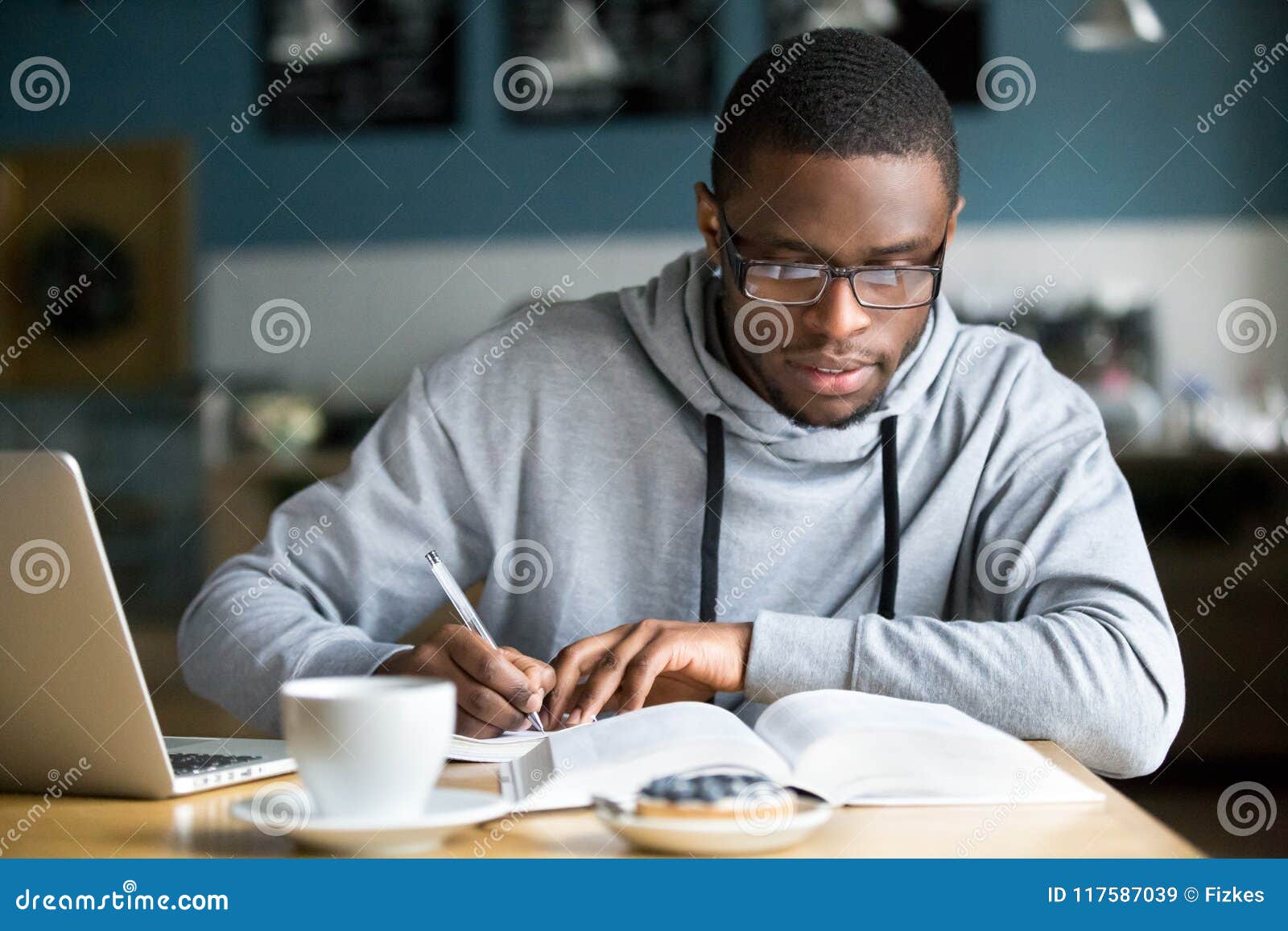 focused millennial african student making notes while studying i