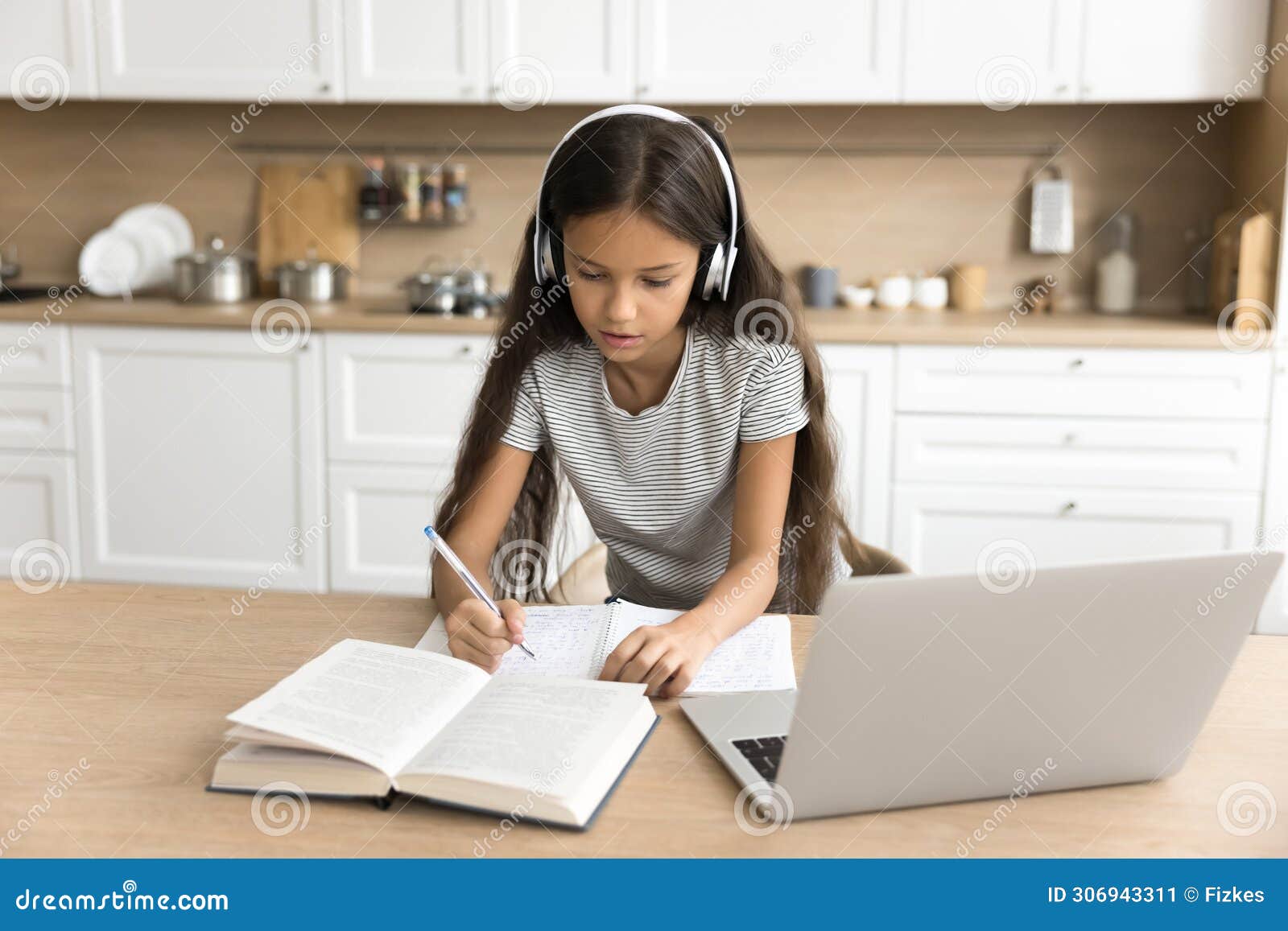 focused pre teen schoolkid girl in headphones studying from home