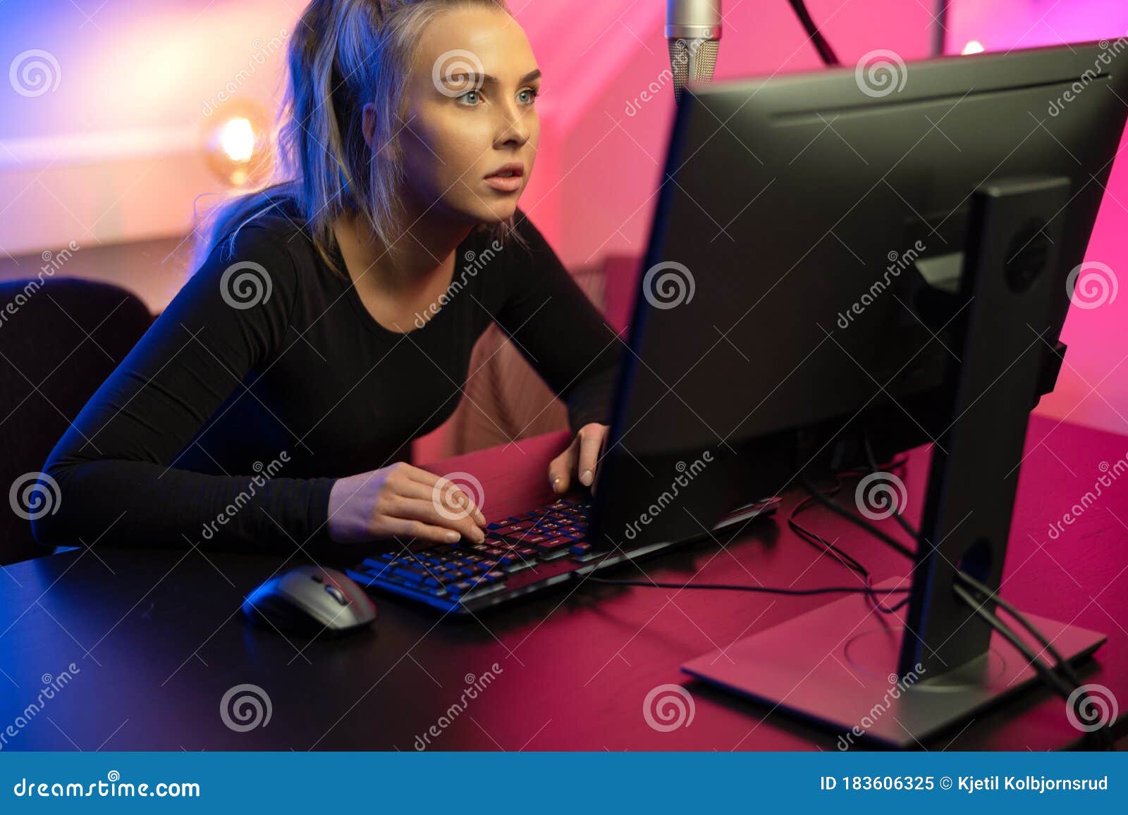 focused professional e-sport gamer girl with headset playing online video game on pc