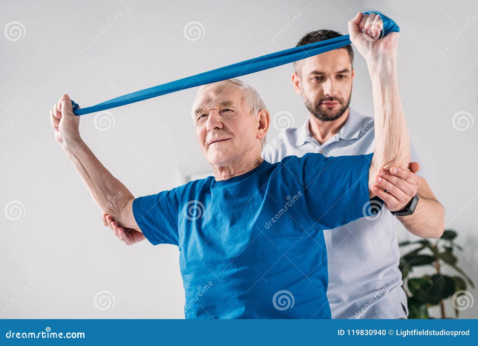 focused rehabilitation therapist assisting senior man