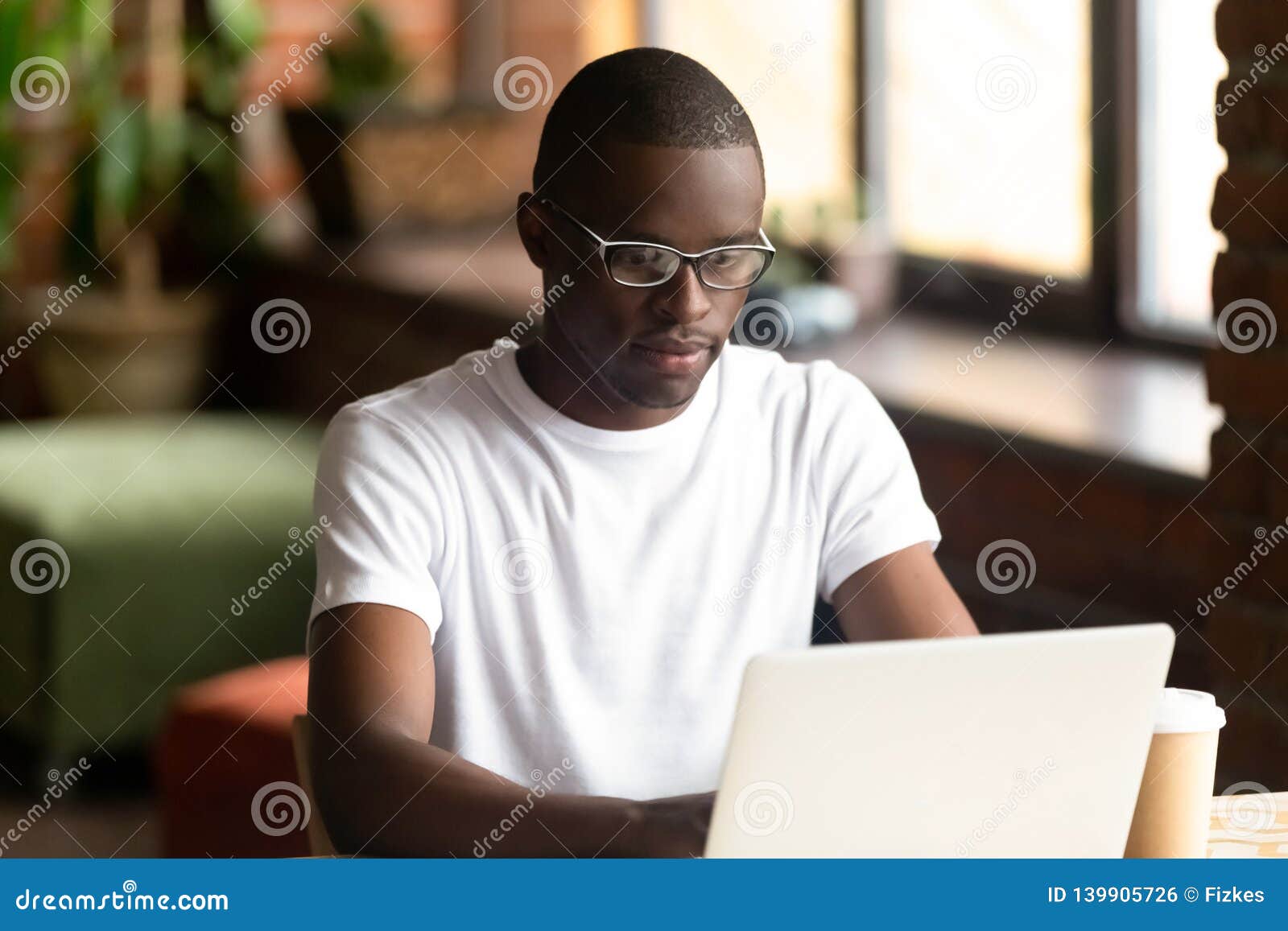 focused black millennial guy working on computer