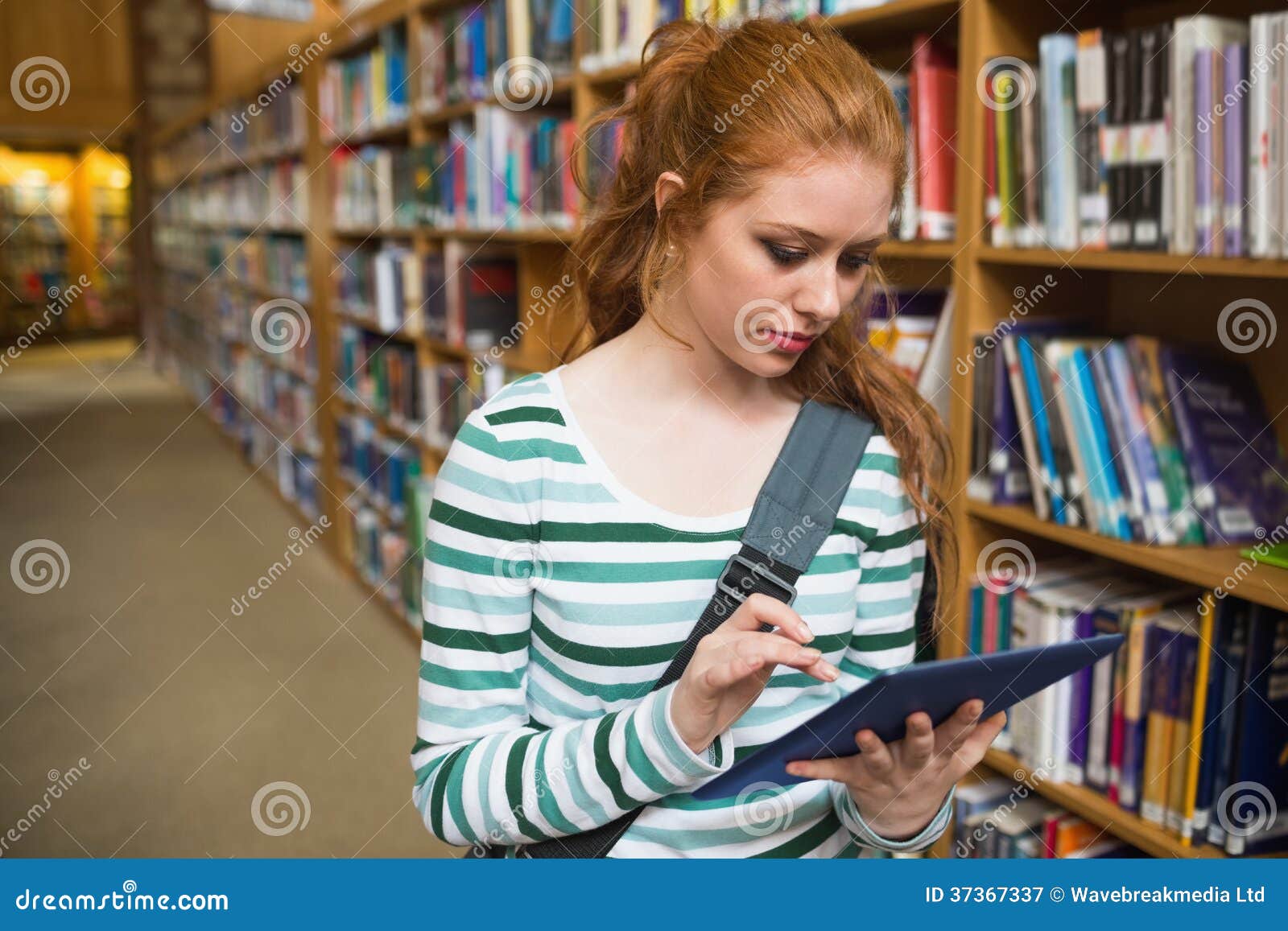 focused student using tablet standing in library