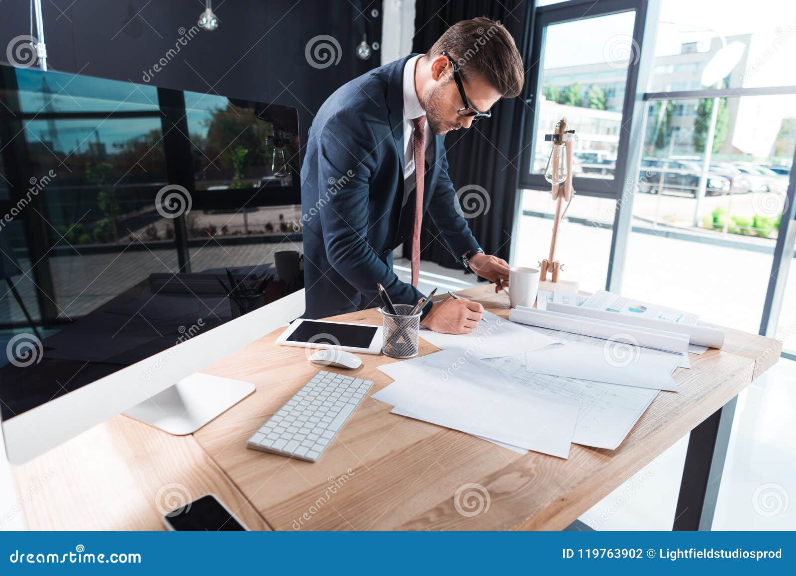 focused young businessman in eyeglasses working with papers