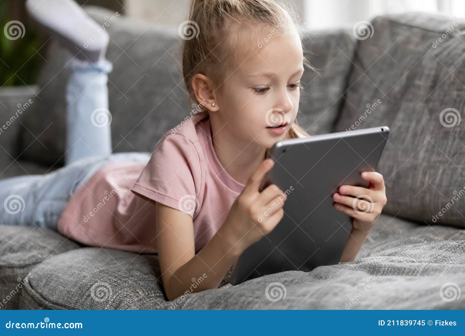 menina bonitinha sentada no chão usando tablet digital tocando a