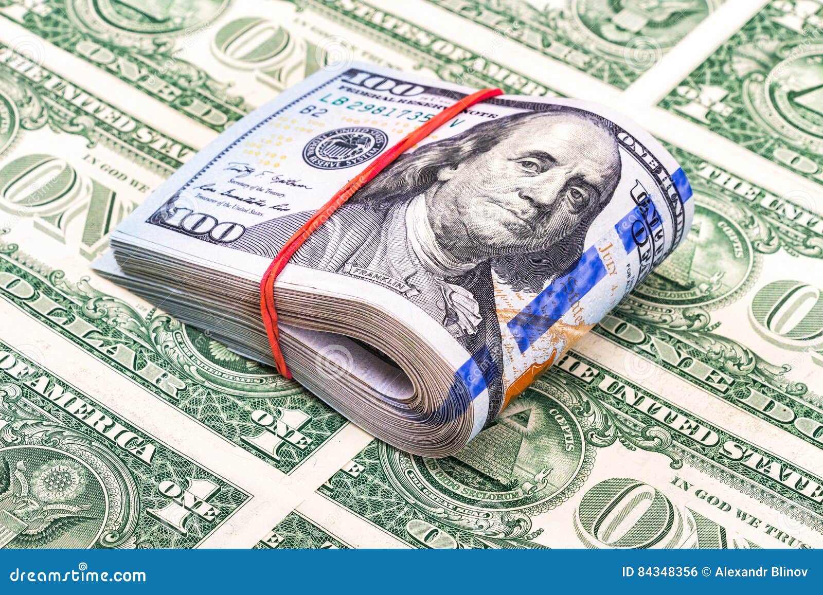 Folded Dollar Bills Wrapped by Rubber Band Over Dollars Stock Photo