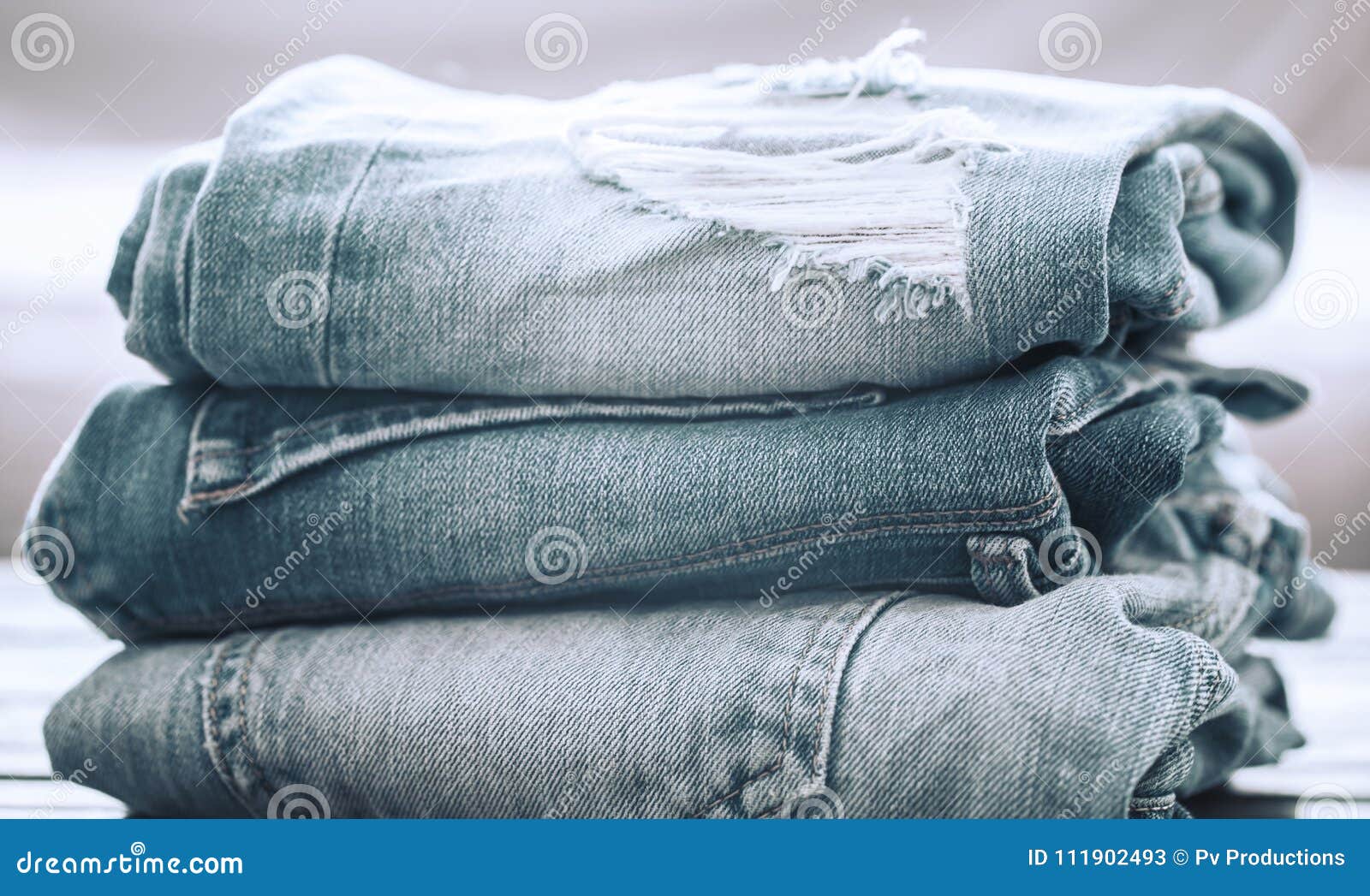 A Stack of Jeans on a Wooden Background Stock Image - Image of fabric