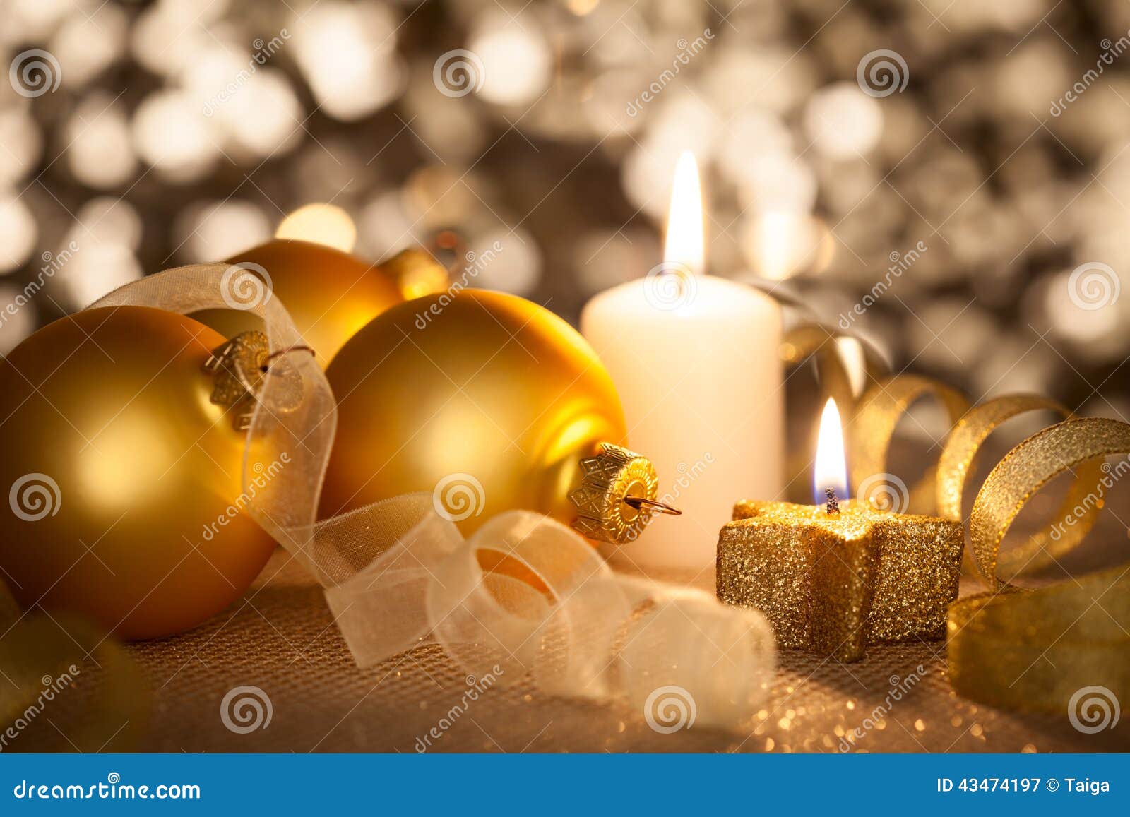 Bello fondo dorato di Natale con le candele, le bagattelle ed i nastri su bokeh