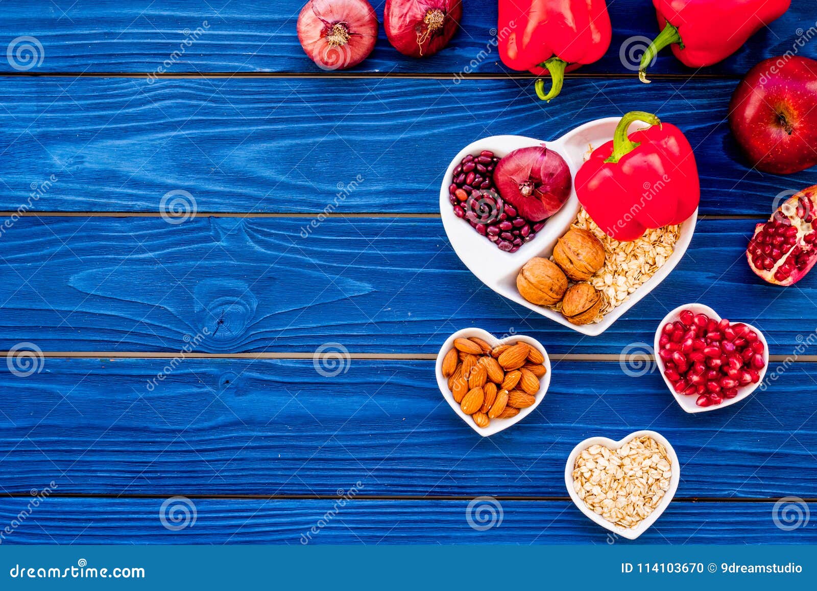 Food which help heart stay healthy. Vegetables, fruits, nuts in heart shaped bowl on blue wooden background top view.