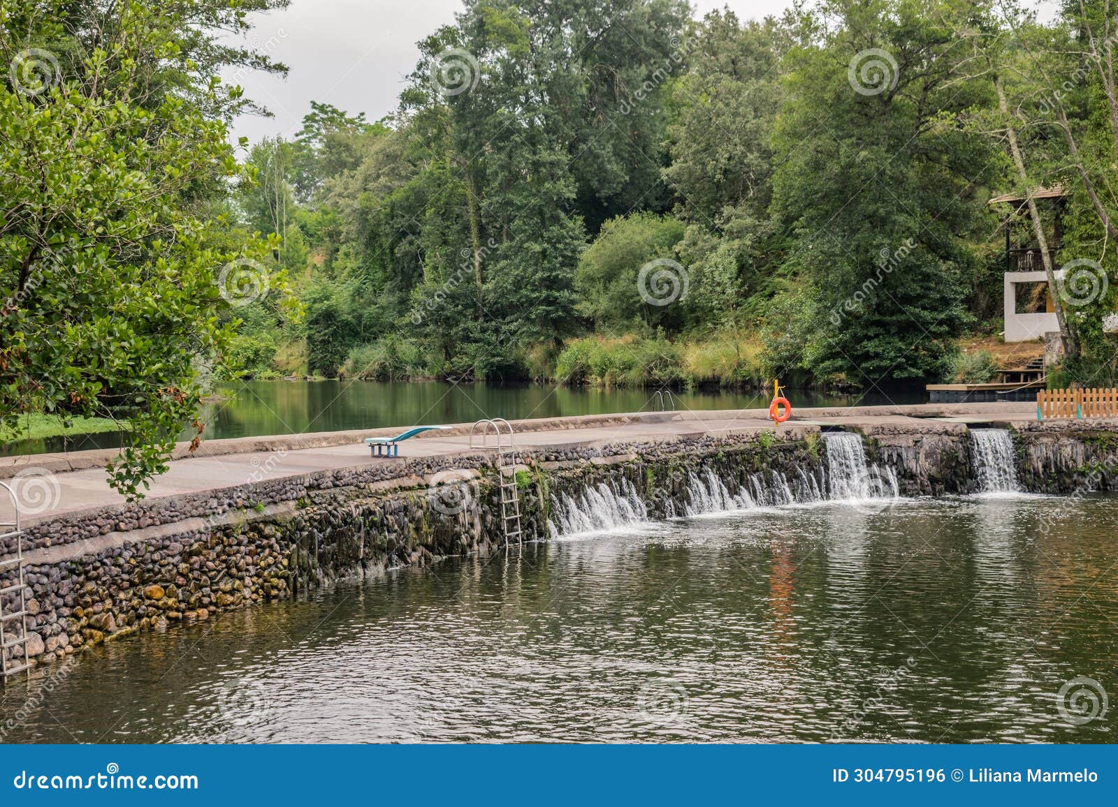 footpath in stone weir with flowing water at coja beach of river alva, arganil portugal