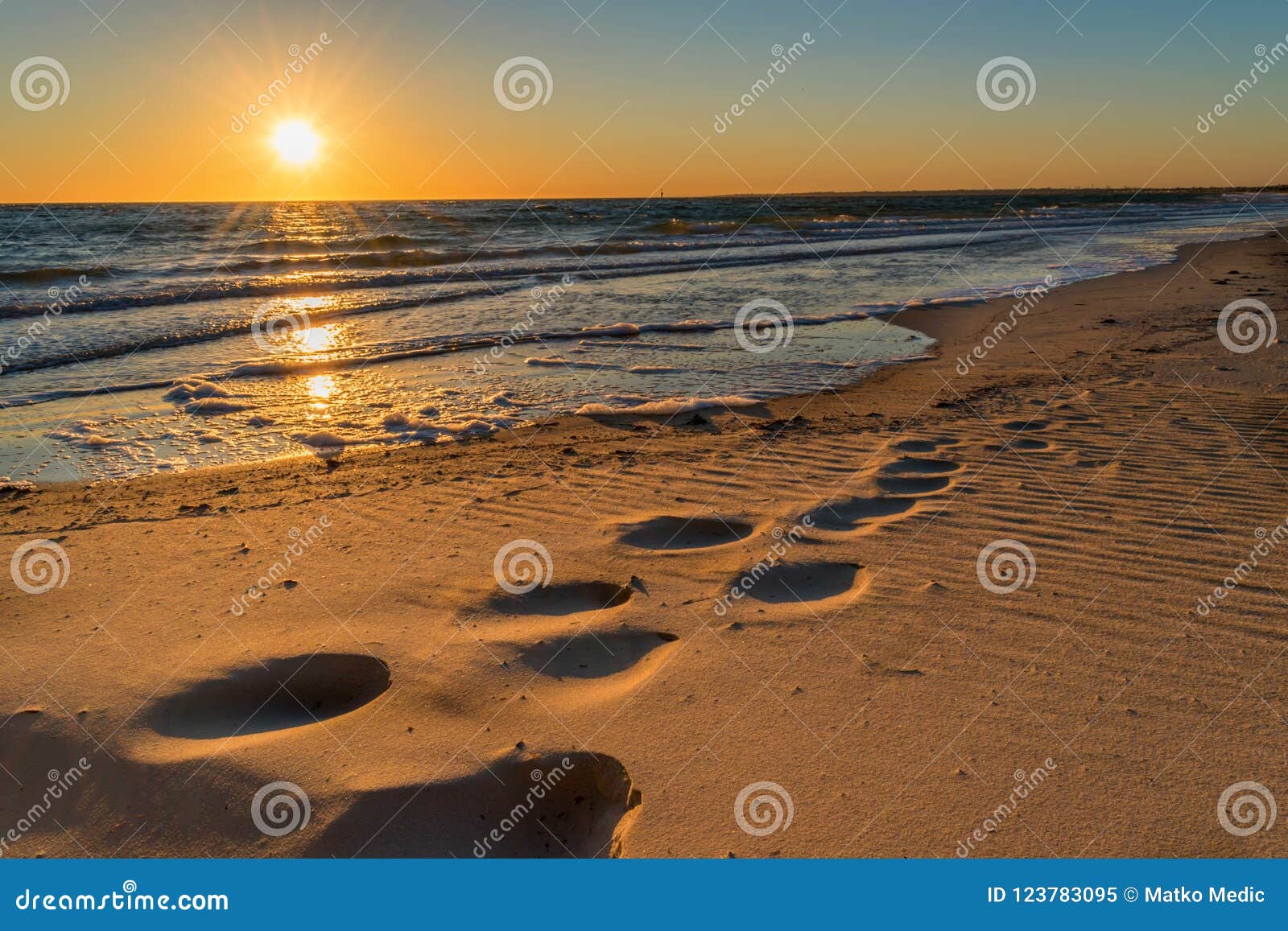 footprints in the sand at sunset