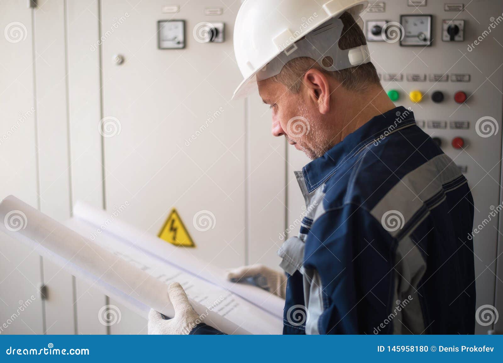 Foreman Electrician Examines the Working Draft Next To the Dashboard