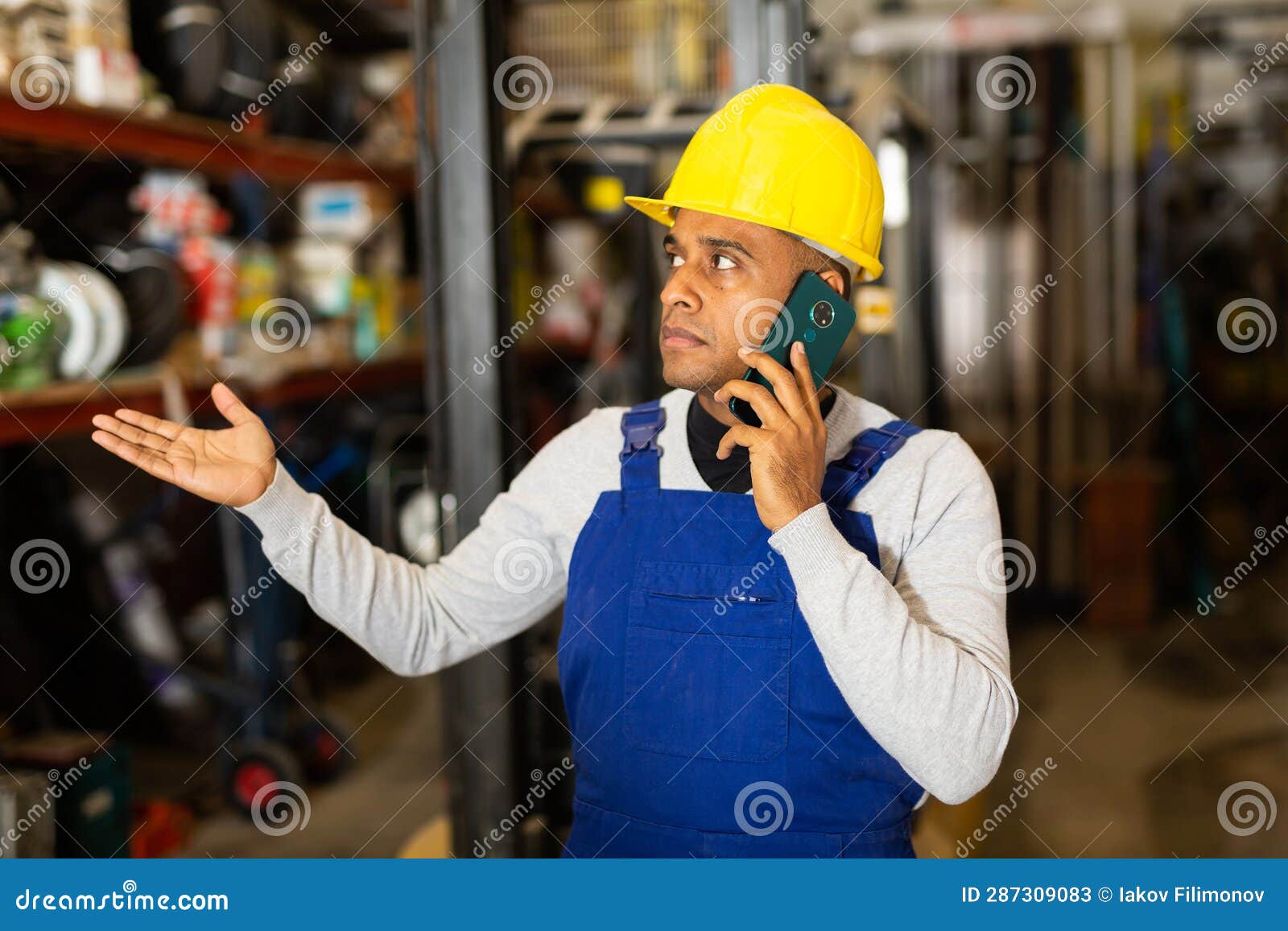 Foreman in Protective Helmet and Overalls Talking on Cell Phone in
