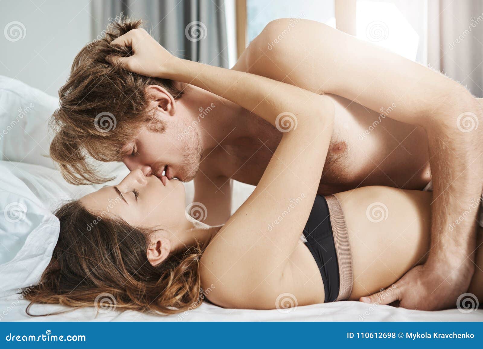 Foreplay Scene of Two Attractive People in Relationship Having Sex in Daytime, Kissing Under Blanket while in Bed Stock Photo