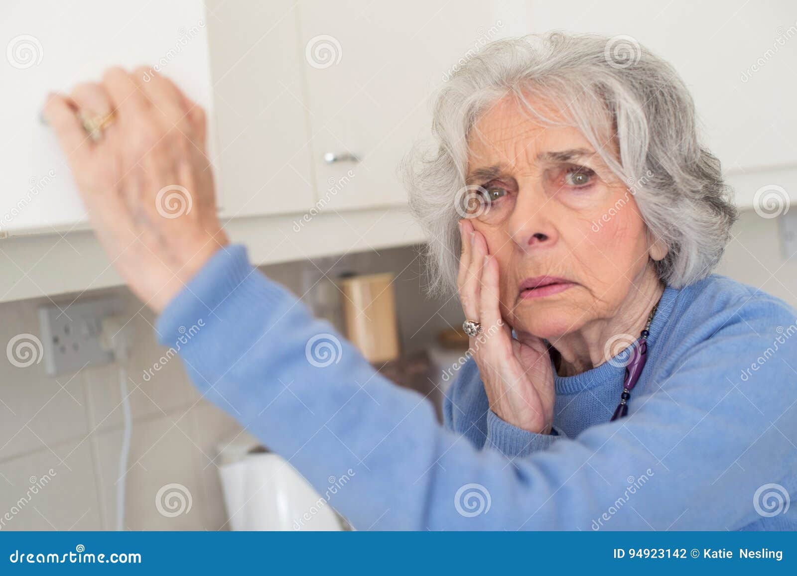 forgetful senior woman with dementia looking in cupboard