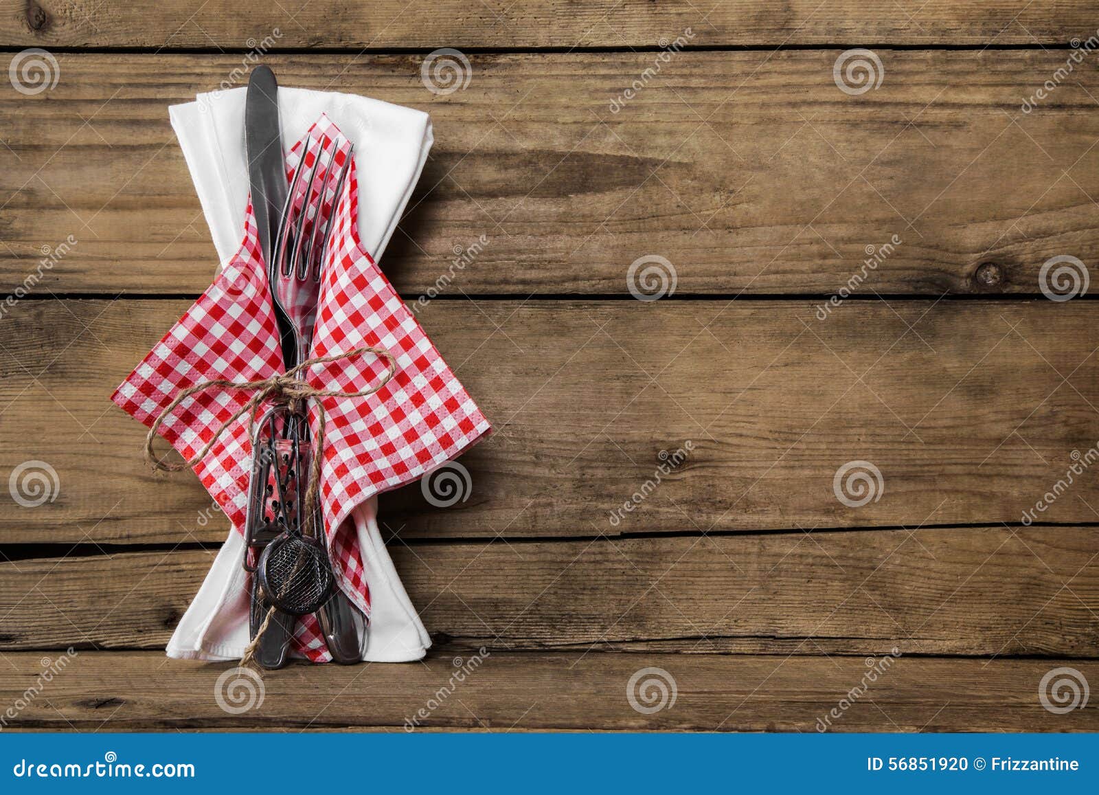 fork and knife set with red white checked napkin on old rustic w