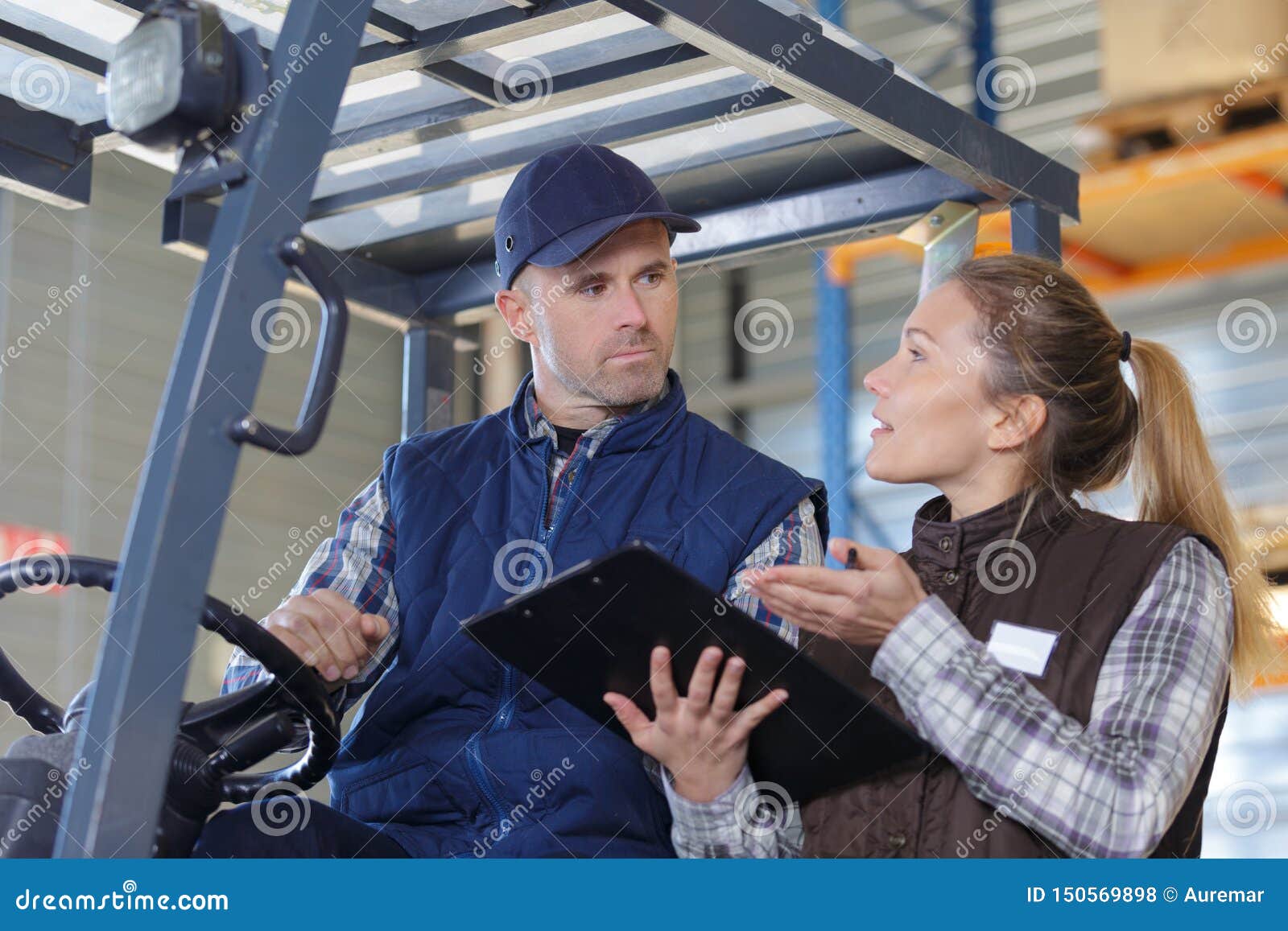 Fork Lift Truck Driver Discussing Checklist with Manager in Warehouse