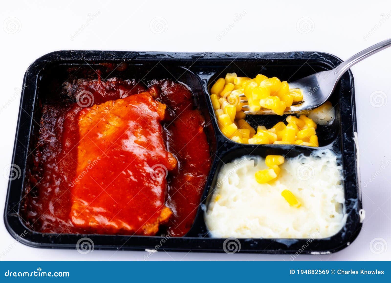 Fork Scooping Some Corn from a Rib TV Dinner in a Tray Stock Image