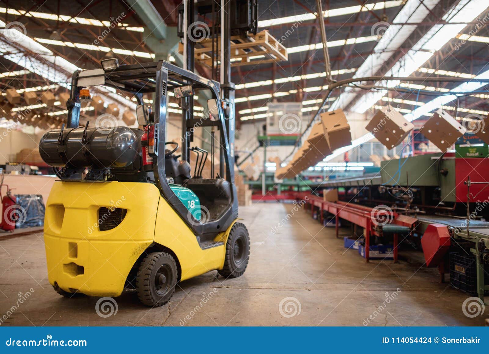 the forklift is in a large and light warehouse. yellow color