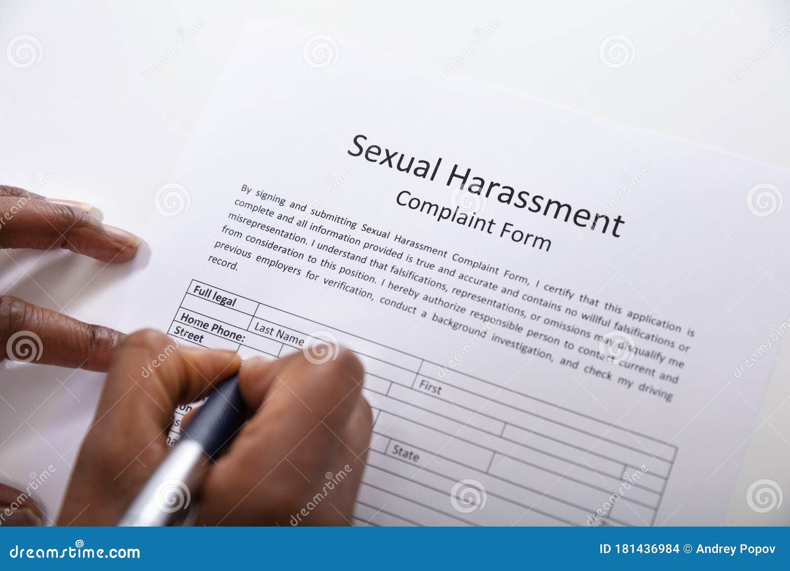 Formulario de denuncia de acoso sexual con mano humana con lápiz