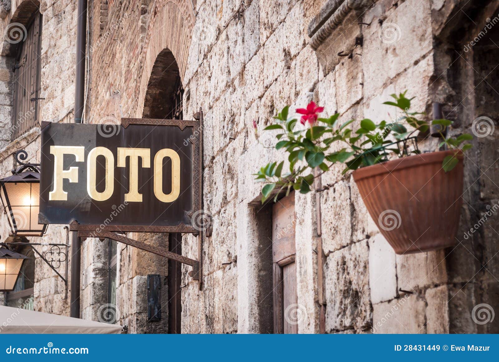 Foto. Signboard on the old buildings wall with flowerpot in foreground