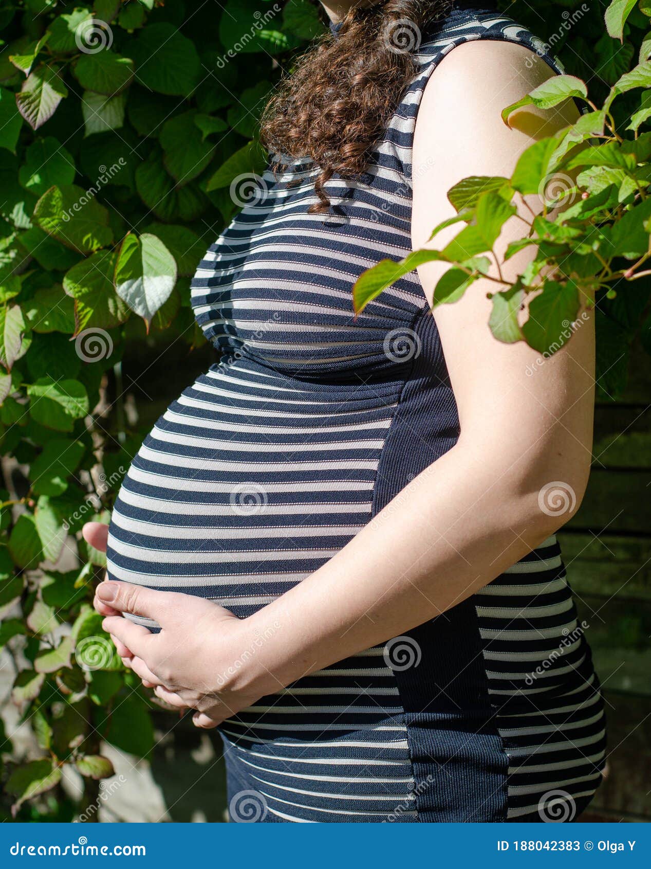 Foto De Una Mujer Embarazada Con Un Vestido a Rayas. Vista Lateral Del  Abdomen. En Perfil. Manos En El Estómago. Contra Imagen de archivo - Imagen  de hembra, verde: 188042383