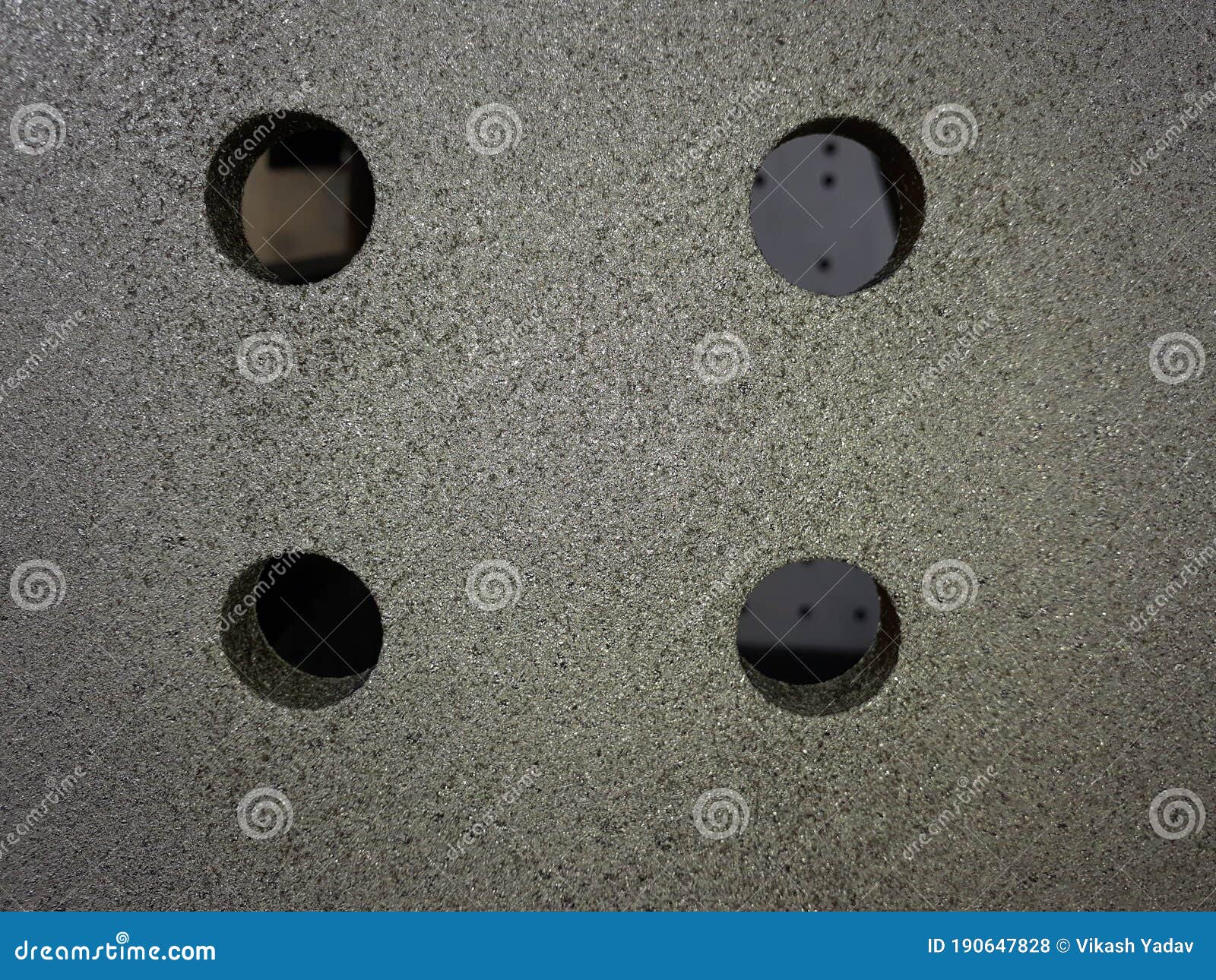 four drilled holes over a blasted clean grey steel surface